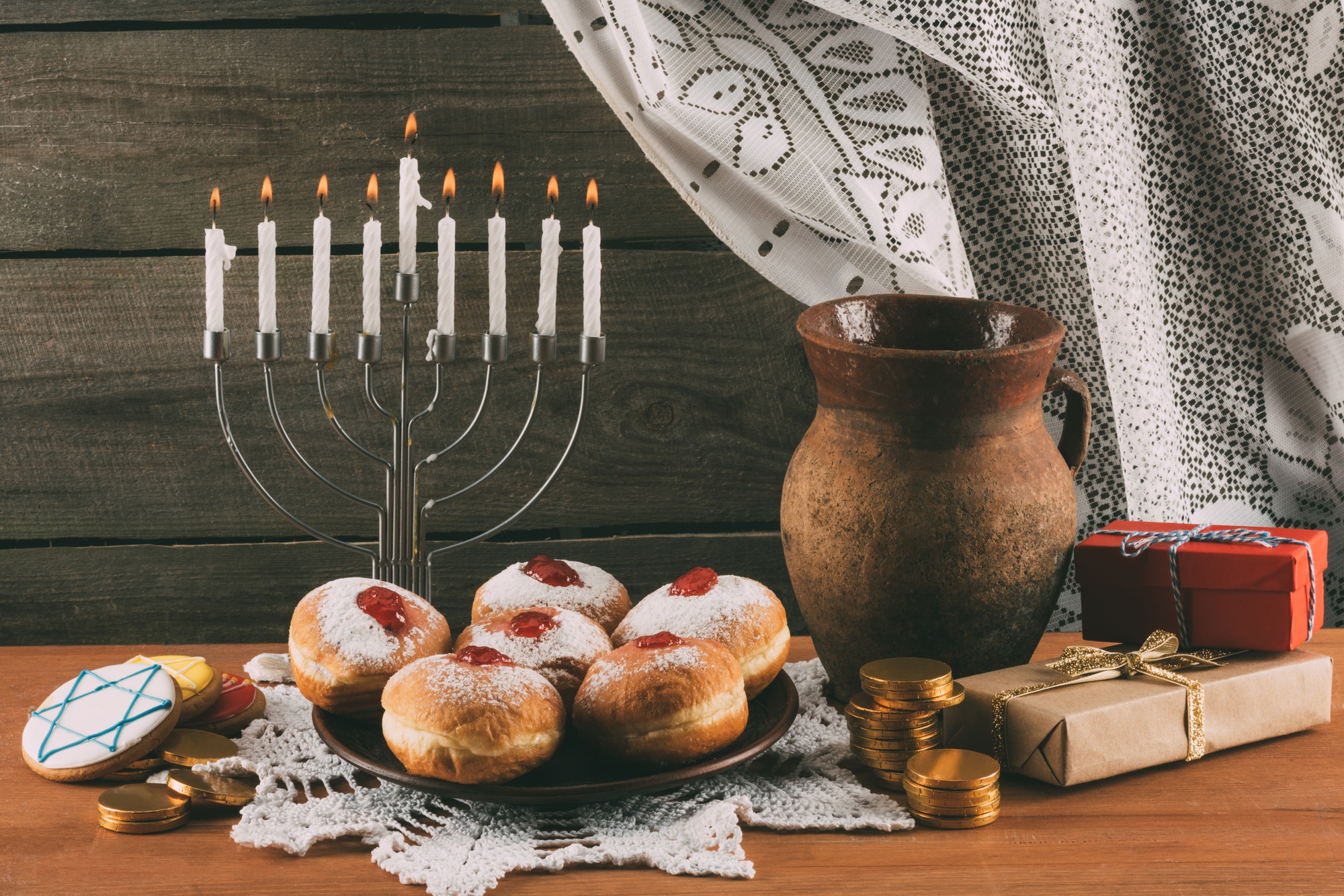 traditional jewish menorah, ceramic jug, Hanukkah gelt, gifts and donuts for hanukkah celebration