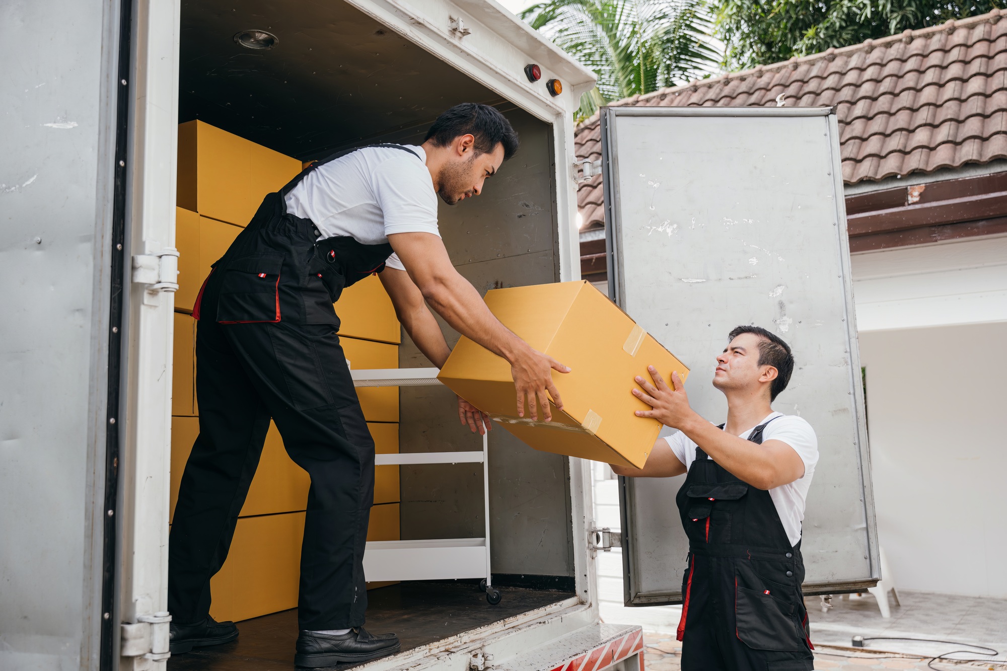 Uniformed employees carry out efficient unloading of cardboard boxes from the truck for customer