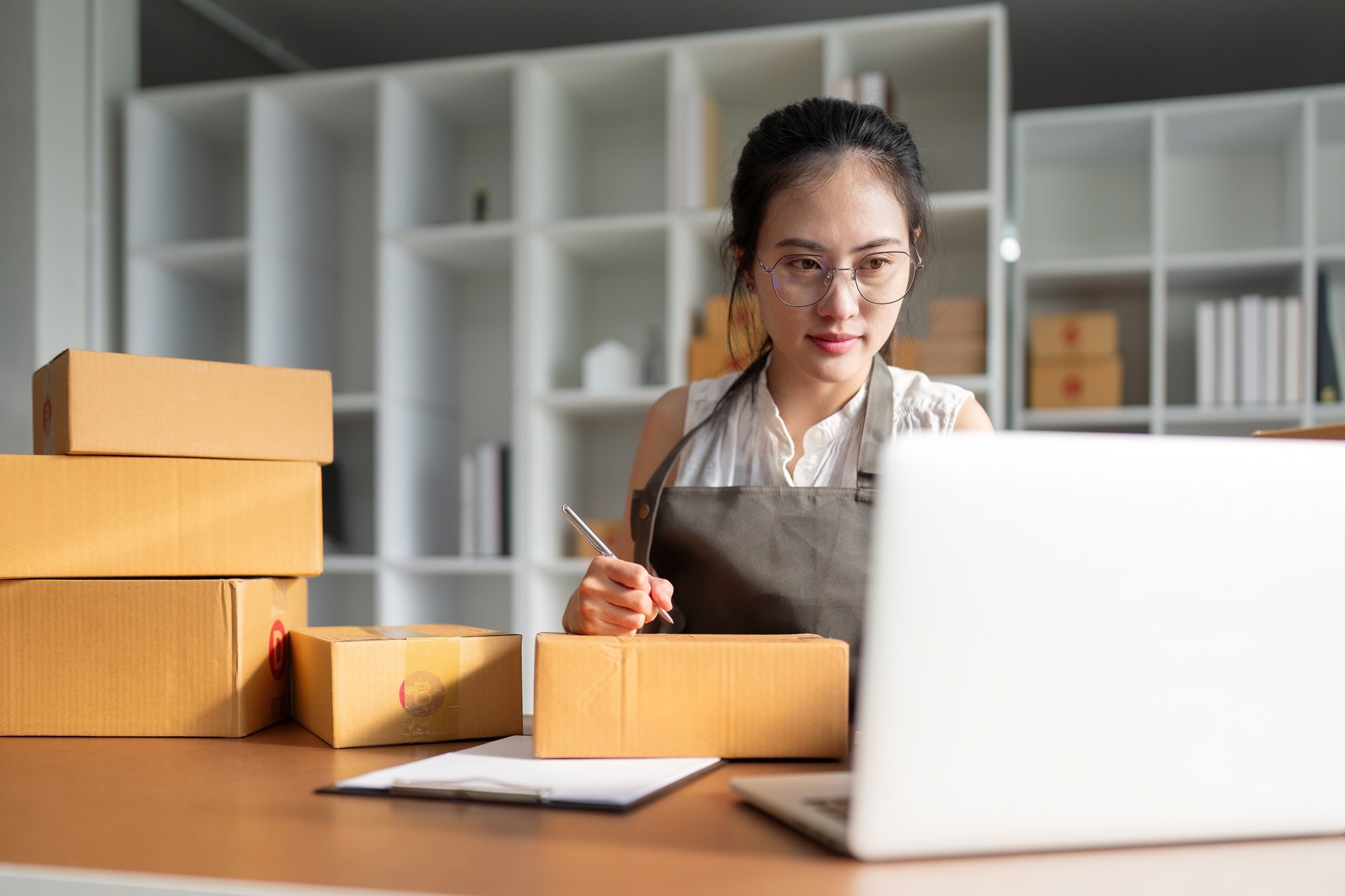 Woman asian is writing a list of customer on paper before shipping to them, she runs an ecommerce