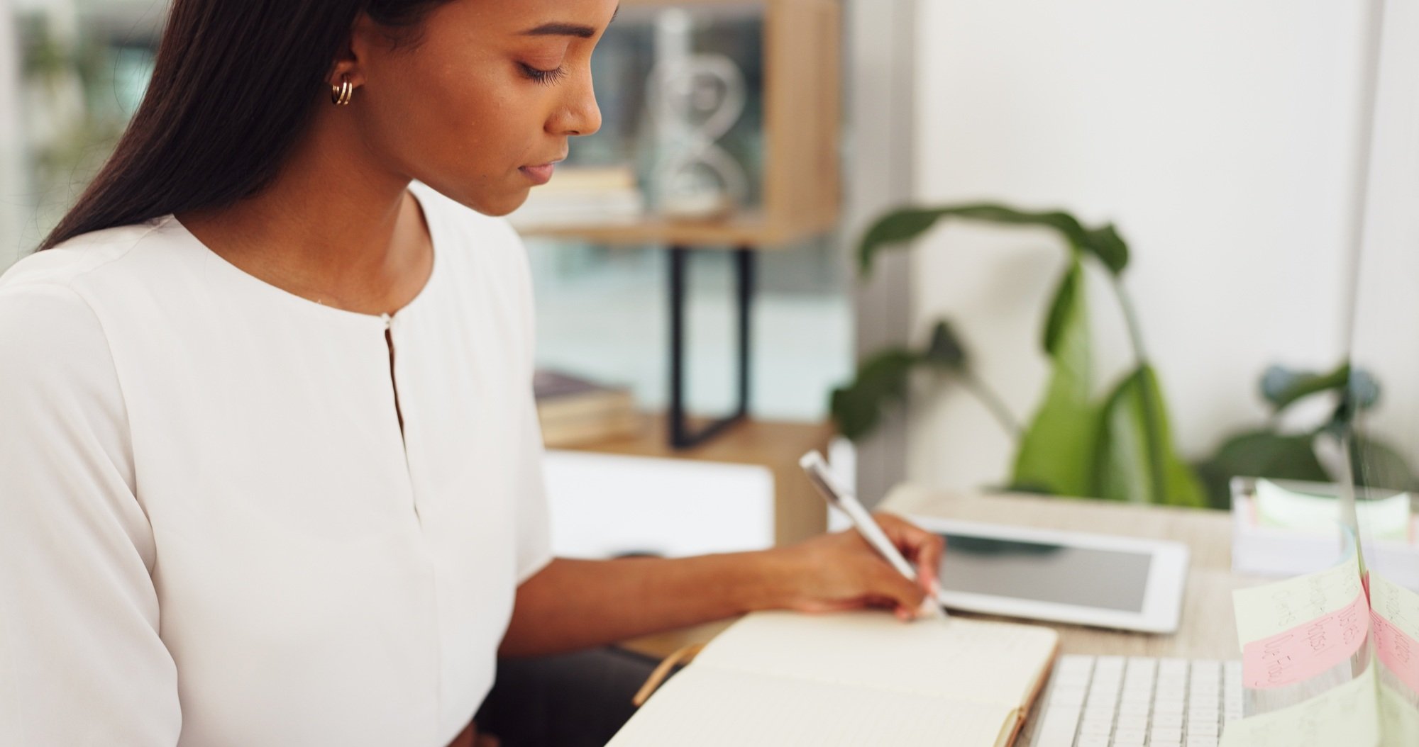 Woman at a computer, writing an email or blog at a desk in the office. Technology, communication an