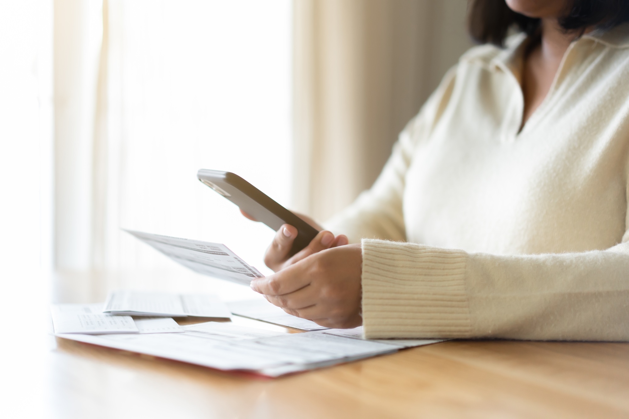 Woman paying bills using mobile phone. Cashless payment concept.