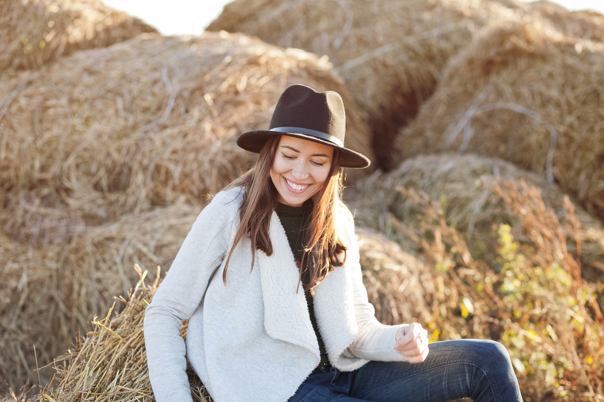 Woman wearing hat sitting on a hay, farm lifestyle, ranch lifestyle, rural, countrytside,real people