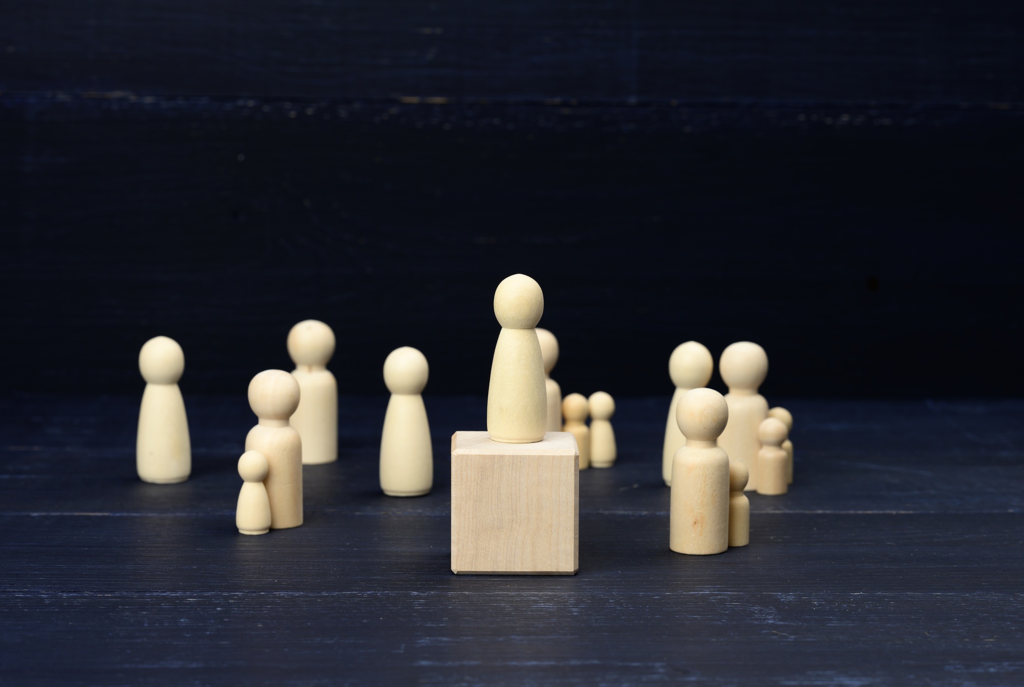 Wooden figurines of men on a blue background. Public speaking concept, leadership and discussion