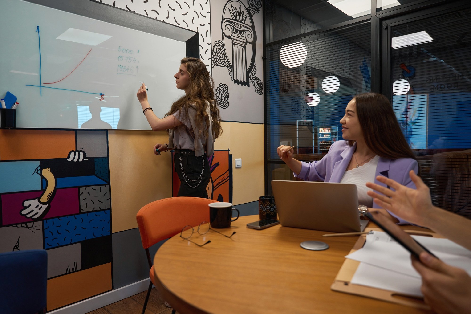 Young employee draws a schedule for colleagues on special board