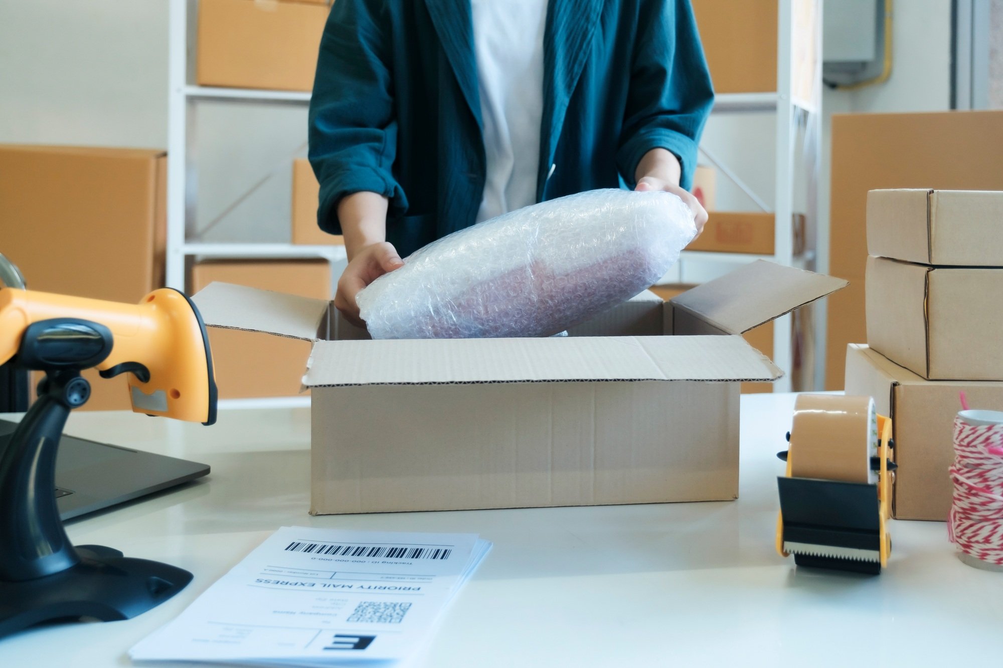 Young entrepreneur packing product in mailing box for shipping.