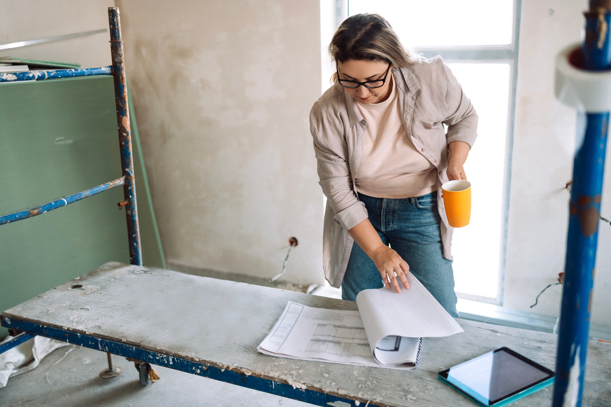 Young female designer checks renovation and house plan.