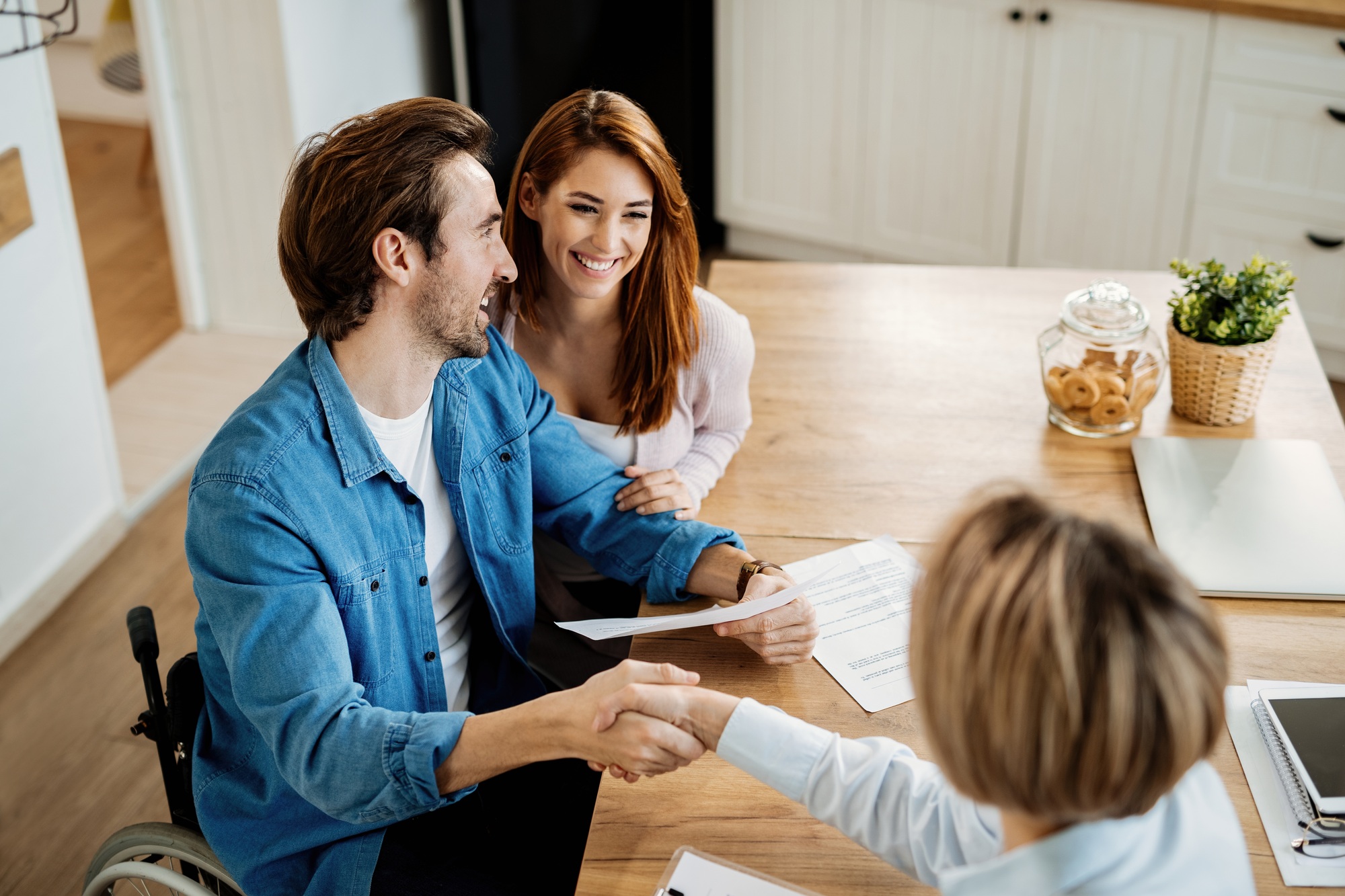 Young happy couple making an agreement with their insurance agent.