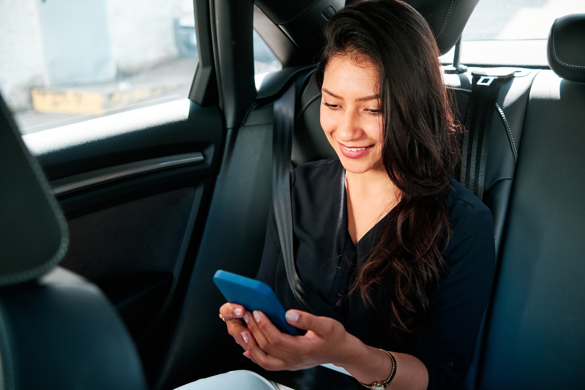 young latin businesswoman using smartphone in her car