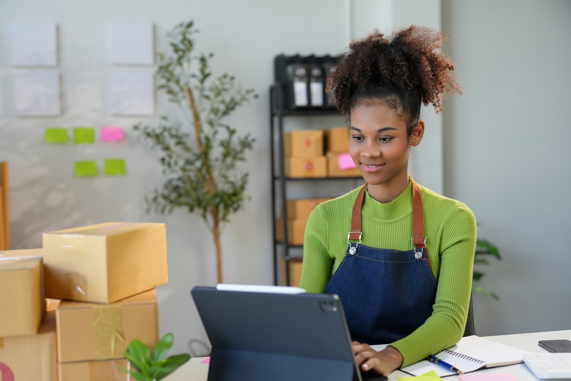 Young woman entrepreneur is smiling while taking online orders on a tablet
