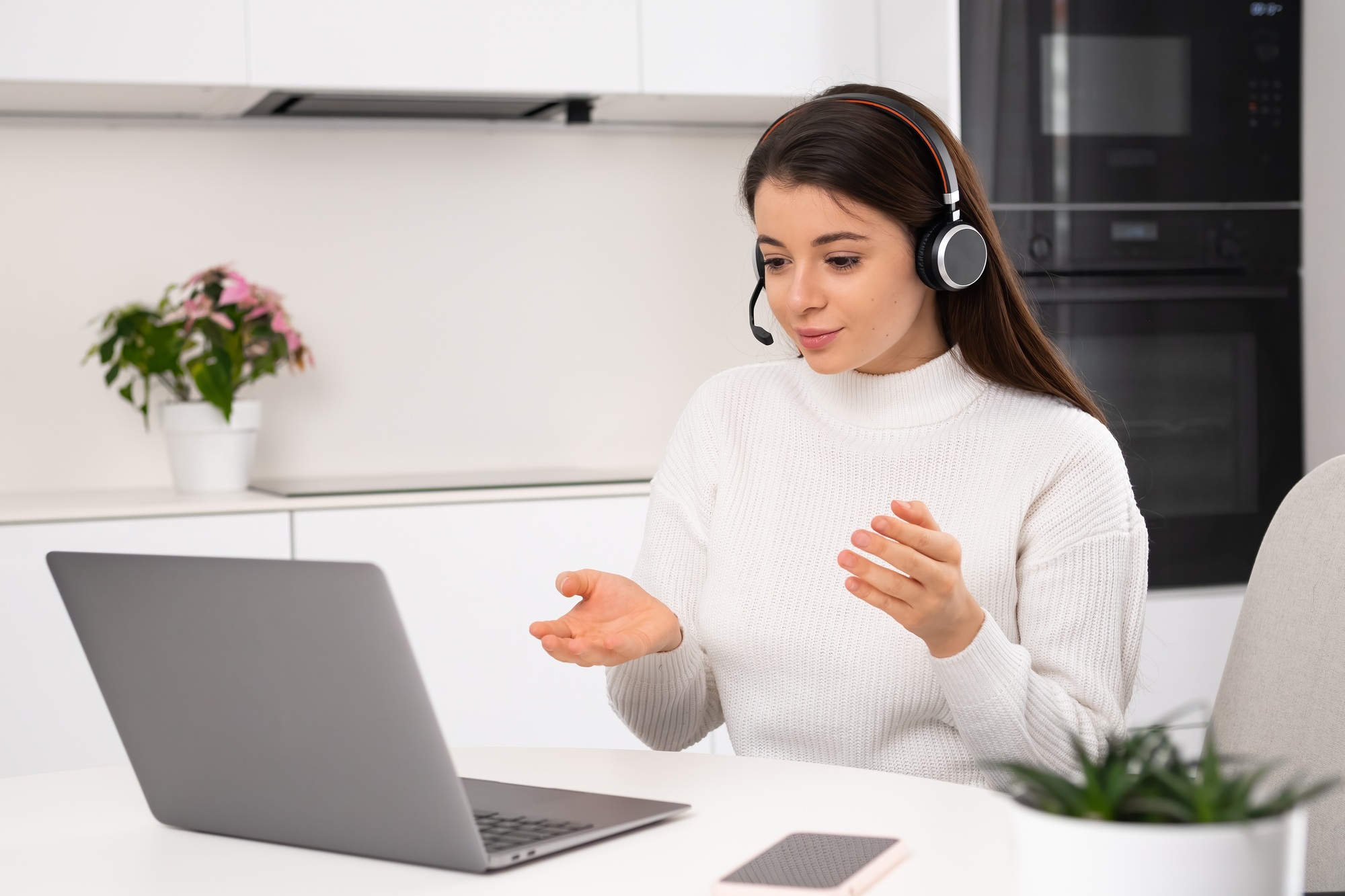 Young woman in headset working online using laptop.