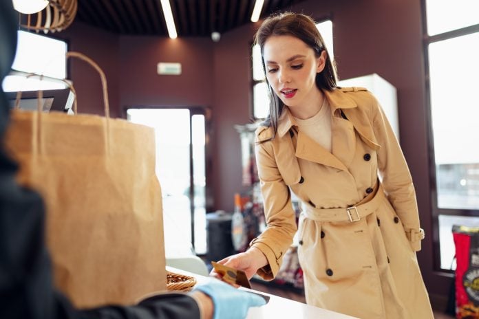 Young woman paying credit card for purchases in grocery store