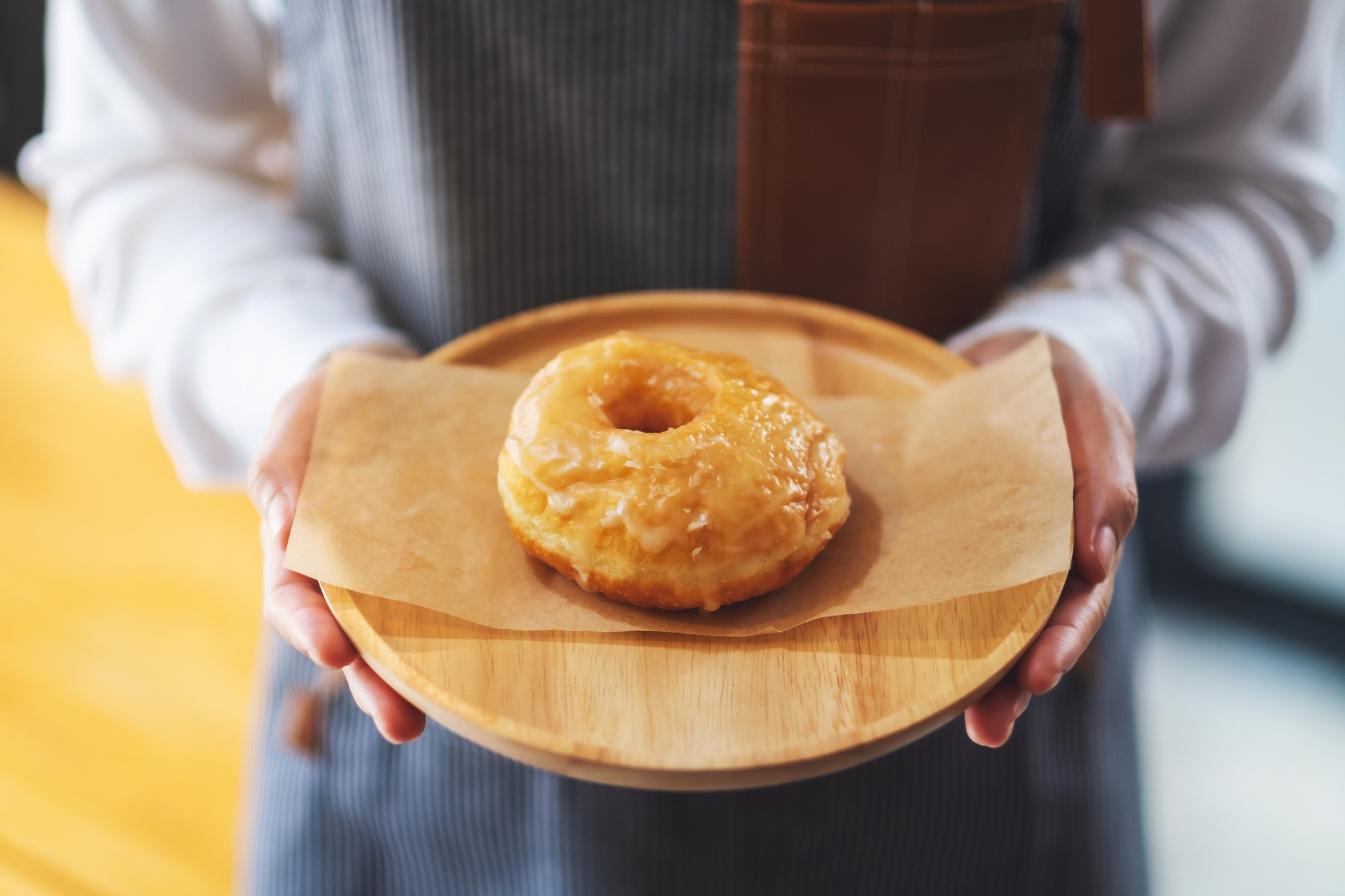A waitress holding and serving a piece of homemade donut in wooden tray