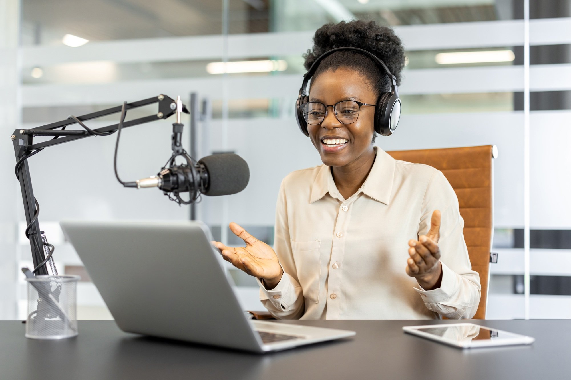 African American businesswoman hosting a podcast with laptop and microphone in modern office
