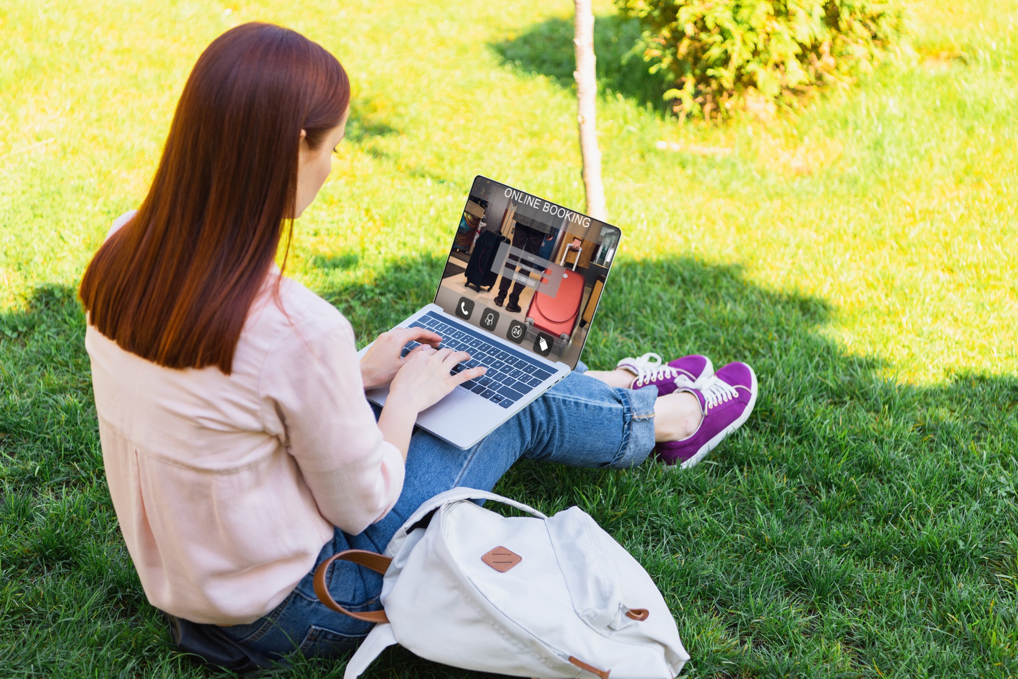 attractive woman using laptop with online booking appliance in park