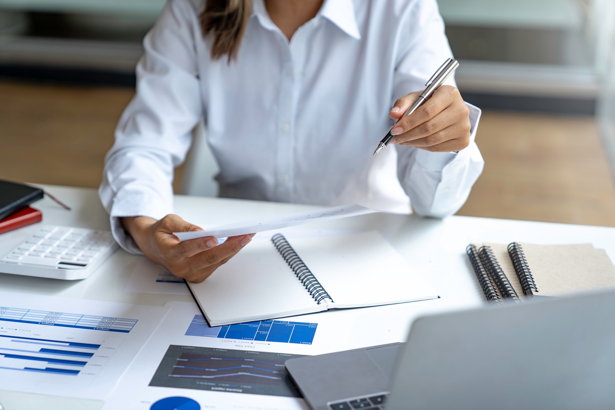 Business woman hand pointing business document and analysis data the charts and graphs at desk.