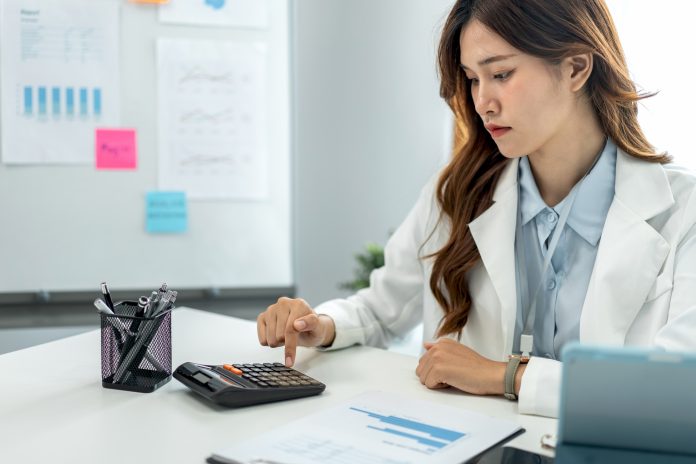 Businesswoman is using calculator to calculate cost and income of business while working to analysis