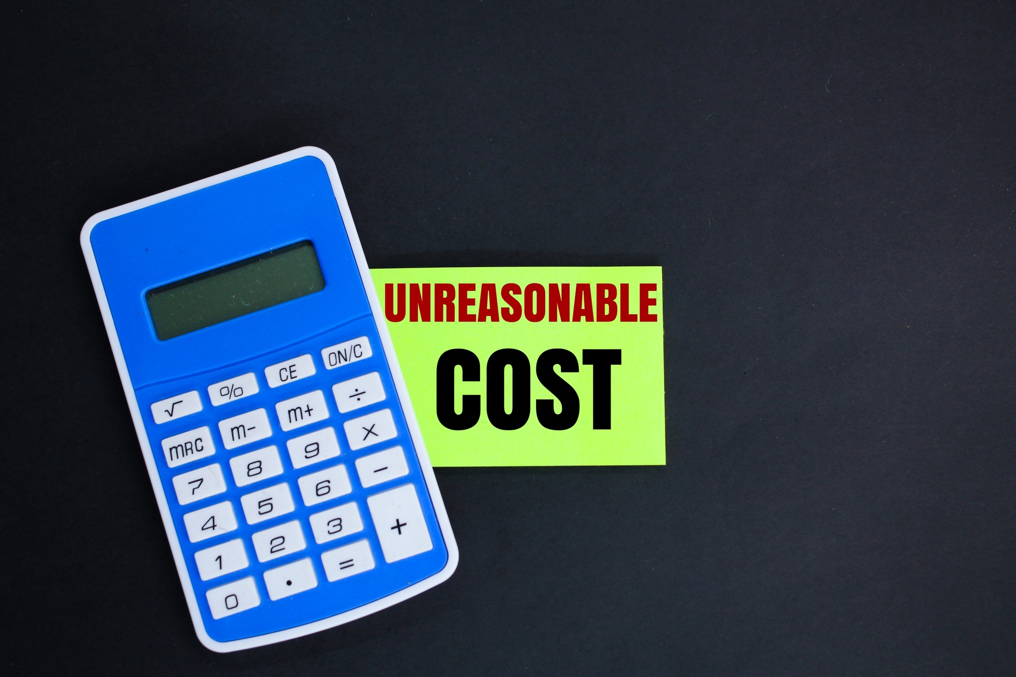 calculator and the word unreasonable cost. concept of cost calculation.