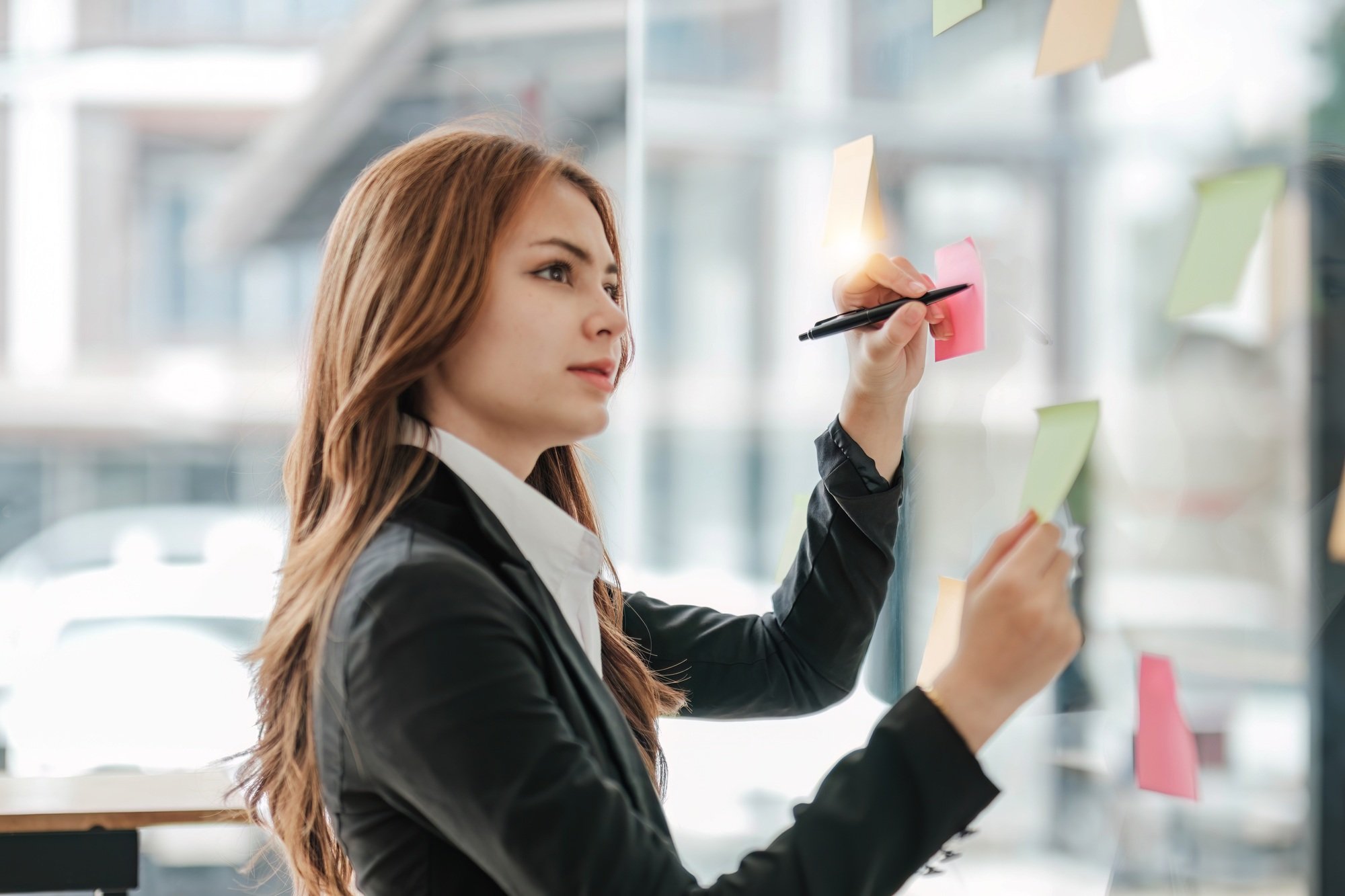 Close-up image of a beautiful young Asian female marketing assistant looking at the sticky note on a
