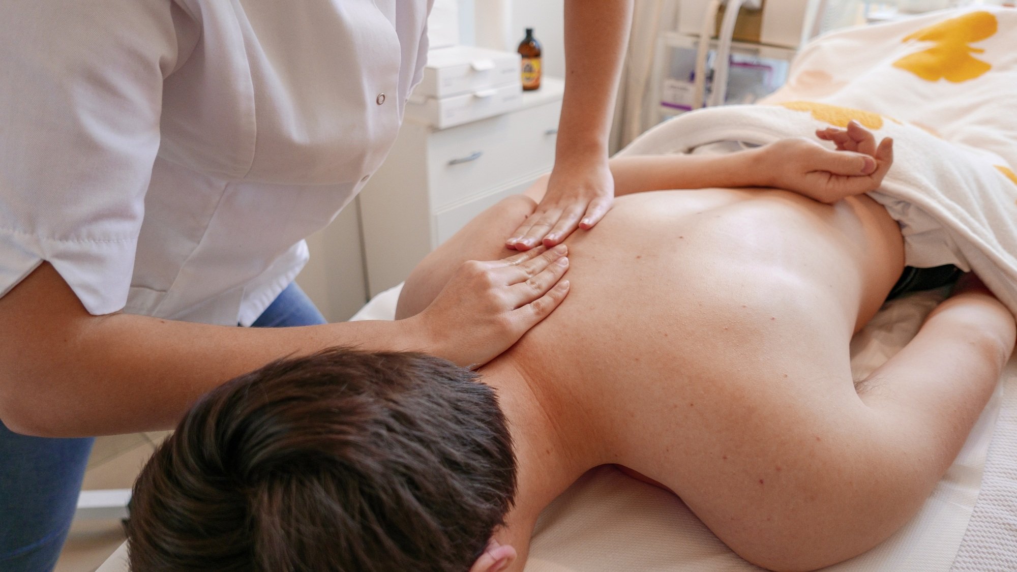 Close-up image of Woman's hands massaging man's back.