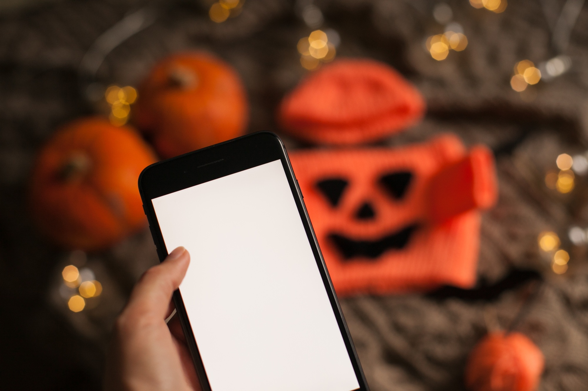 Holding mobile phone to make some halloween online shopping