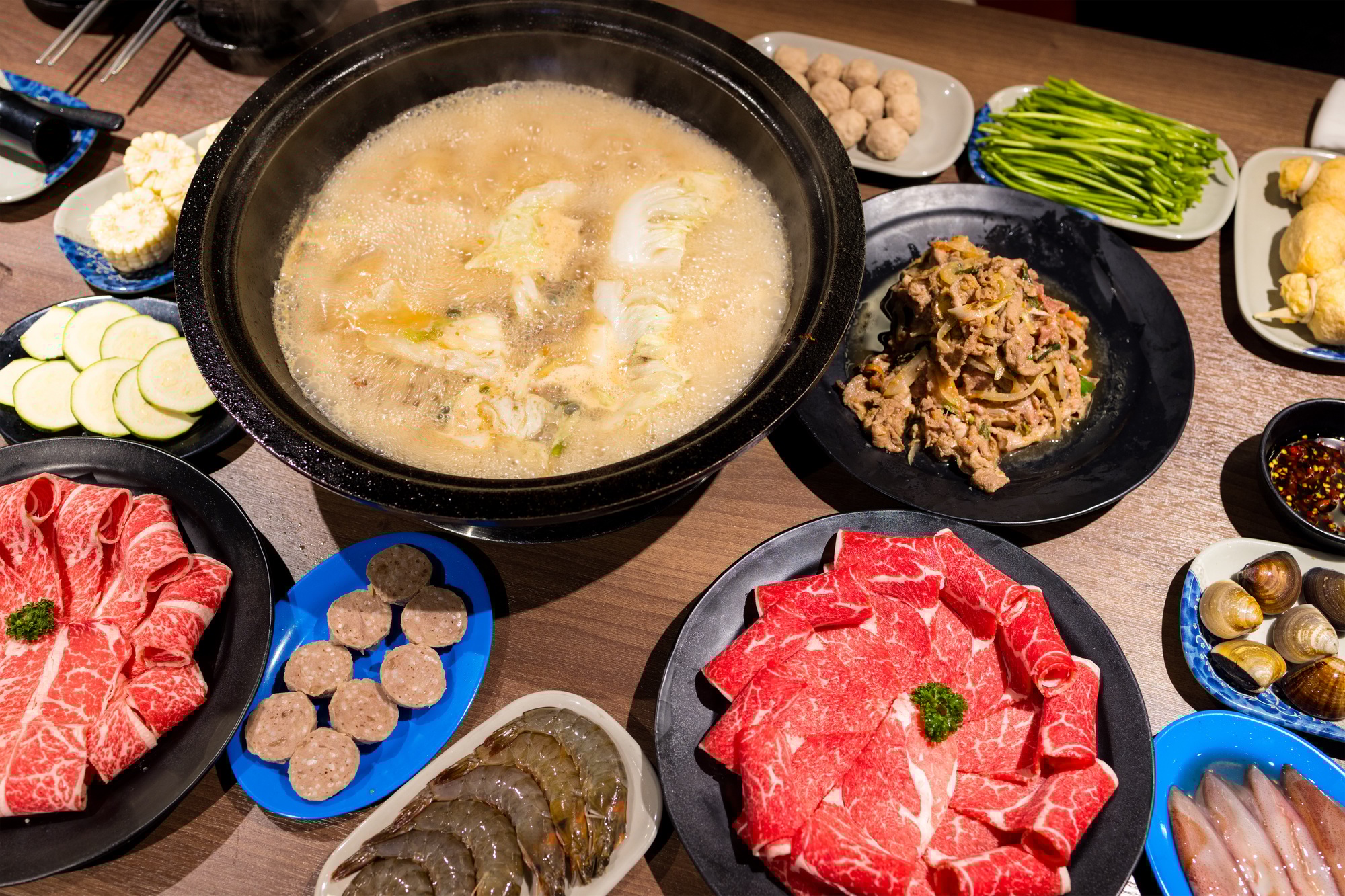 Hot pot with lots of food on the table