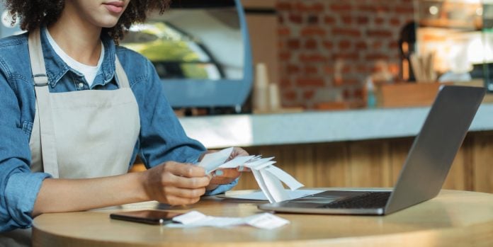 Millennial african american woman owner manager in apron works with account and bookkeeping in cafe