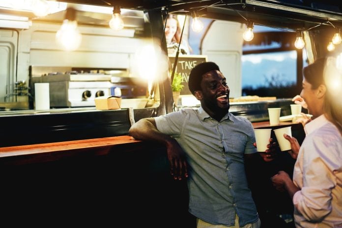 Multiracial people cheering with drinks in counter at food truck restaurant outdoor