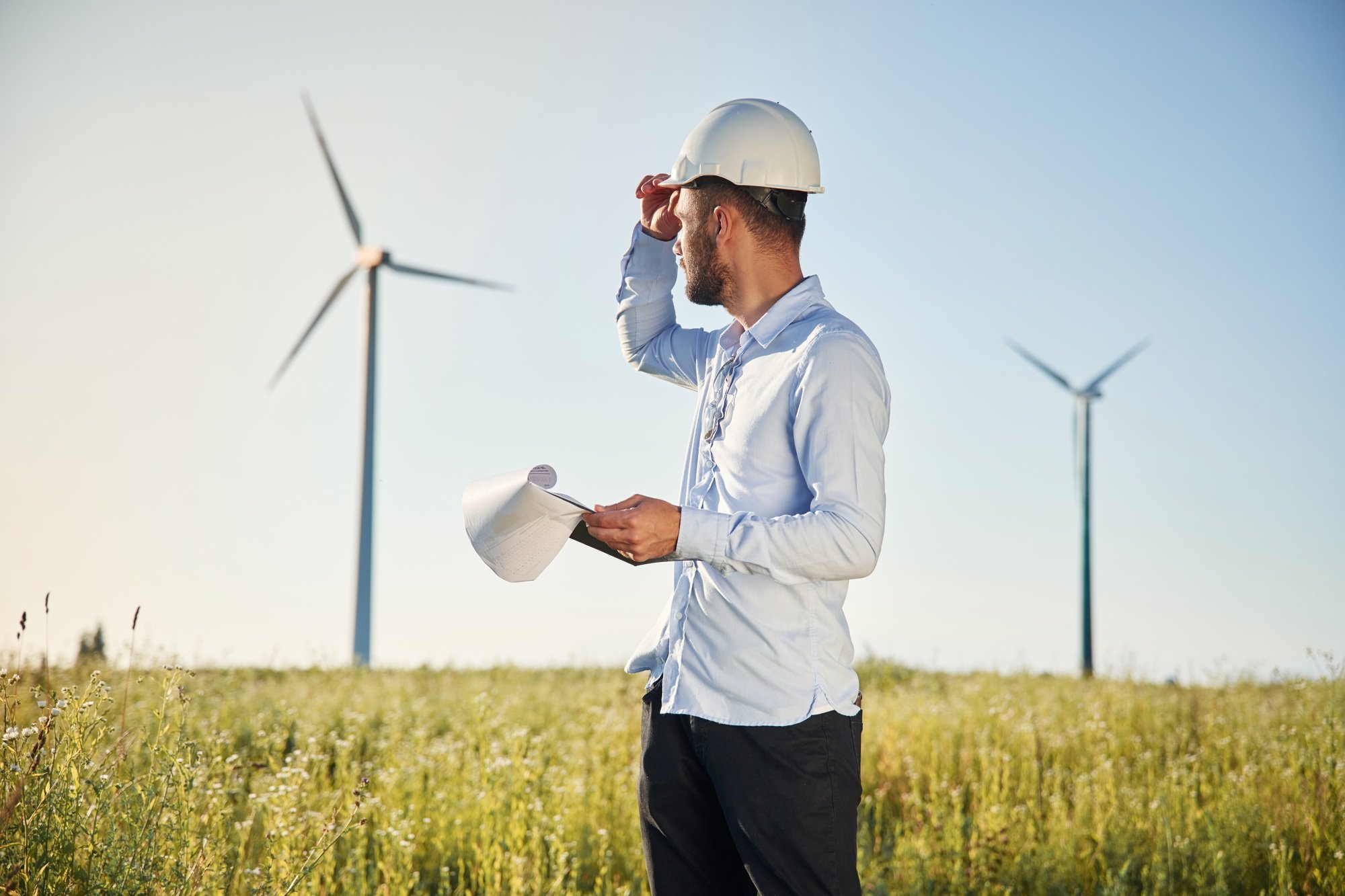 On the field with windmills. Service engineer with notepad in hands