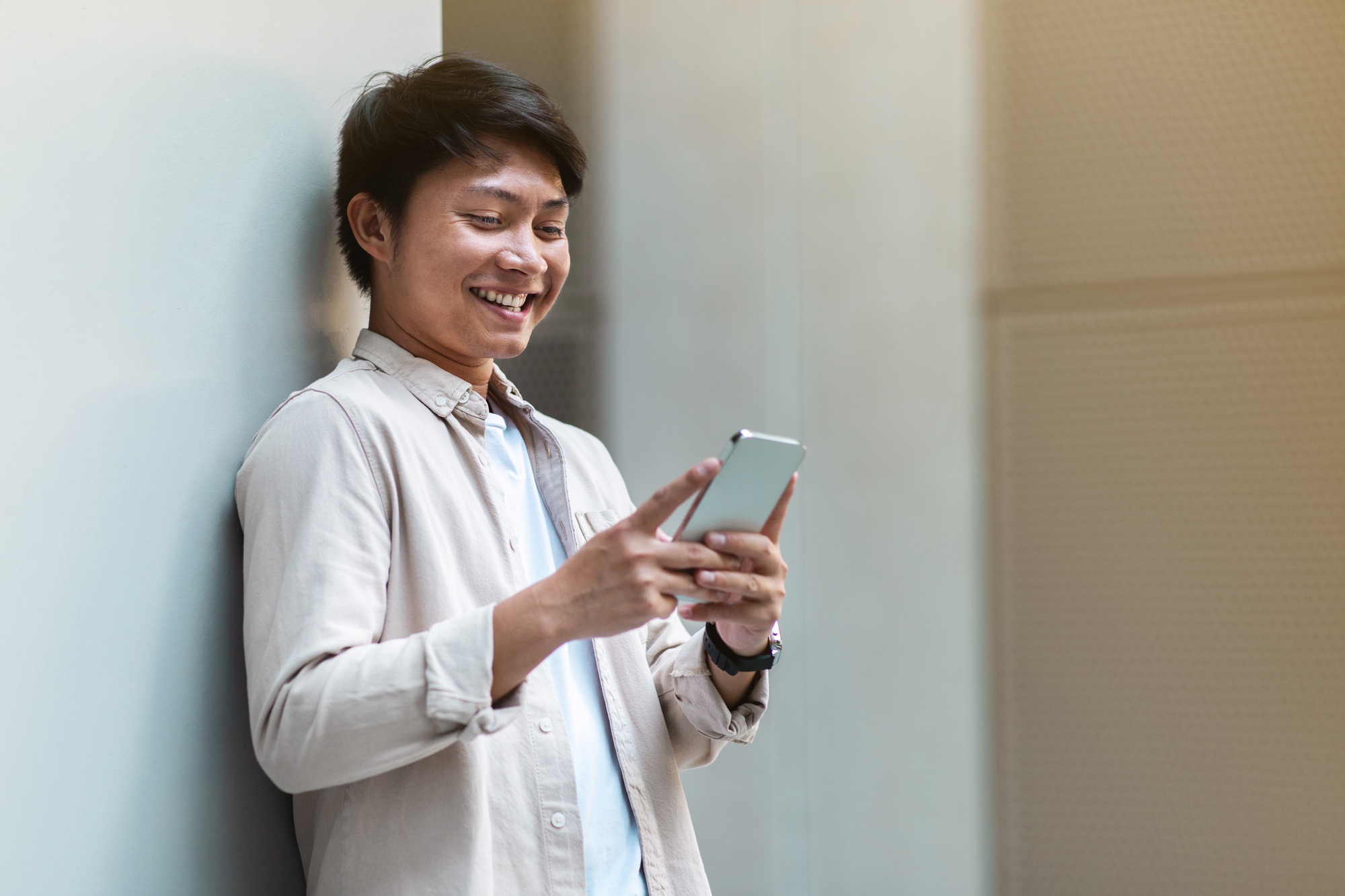Positive chinese guy employee have break, using phone outdoors