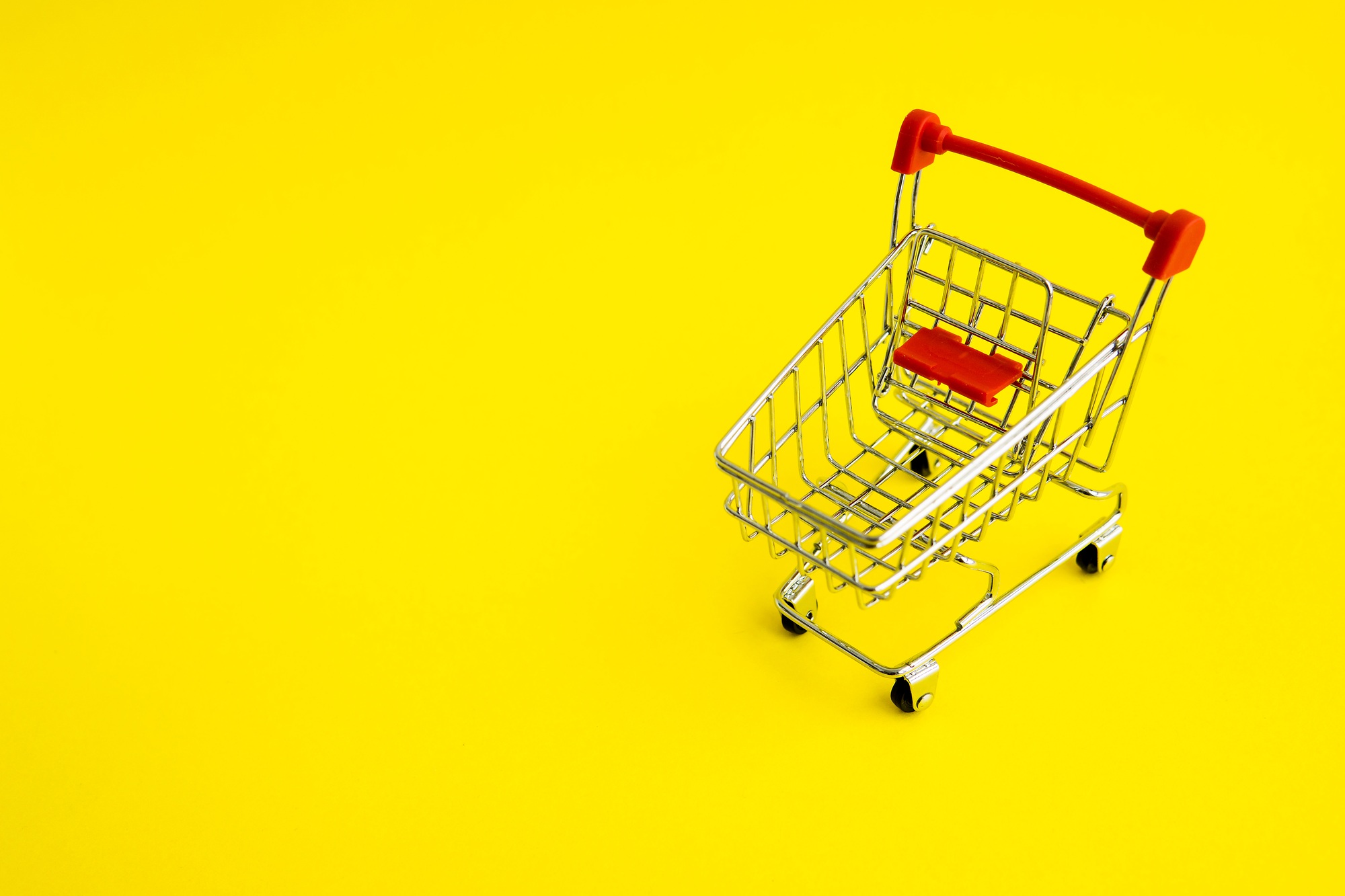 shopping cart on a yellow background. Theme of purchases and sales.