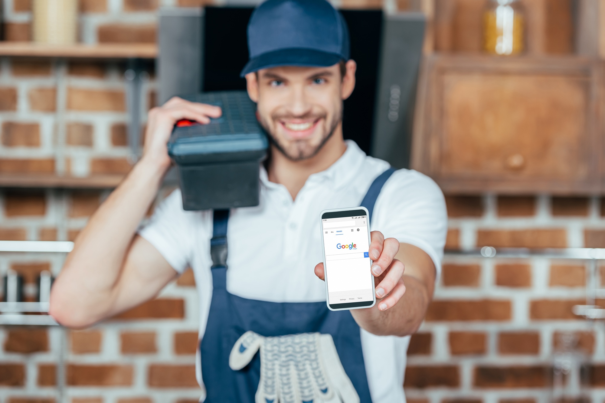 smiling young home master holding smartphone with google website