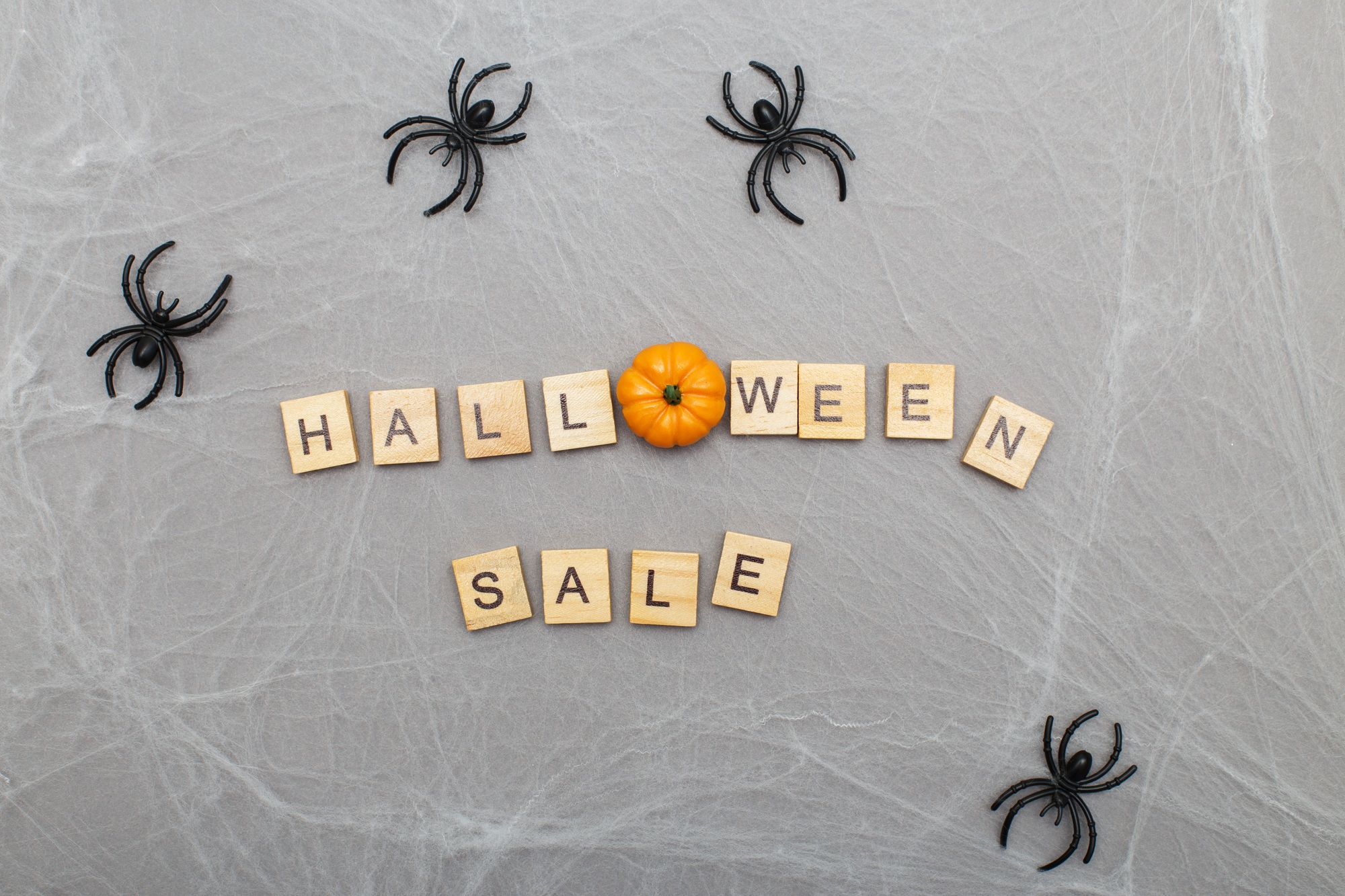 the inscription halloween with spider web and spiders on a gray background