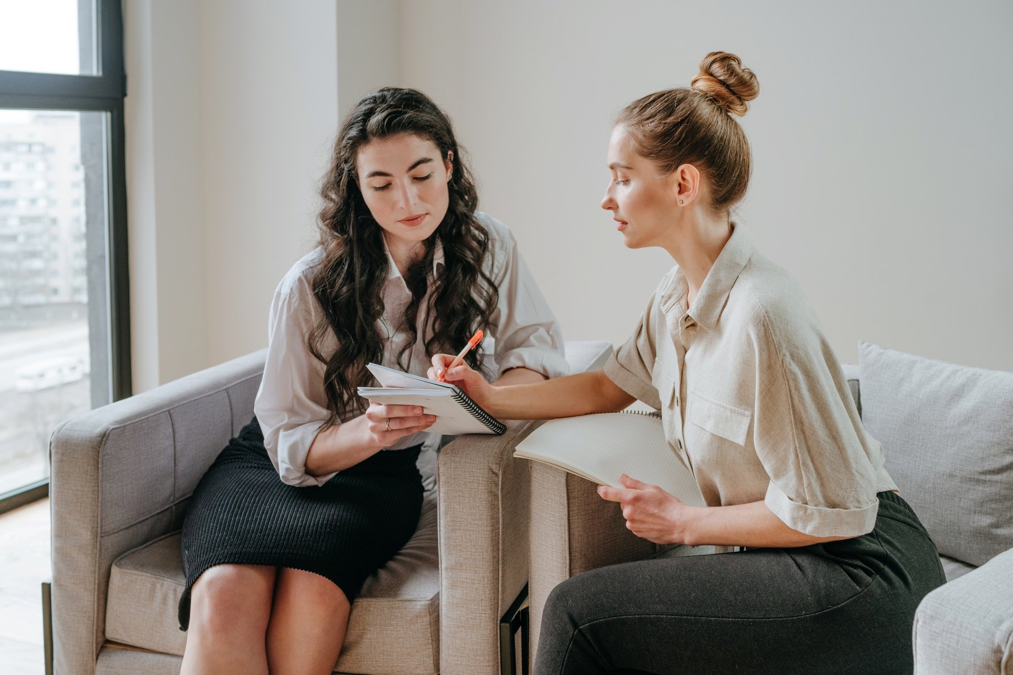 Two women colleagues discussing business ideas at workplace in office