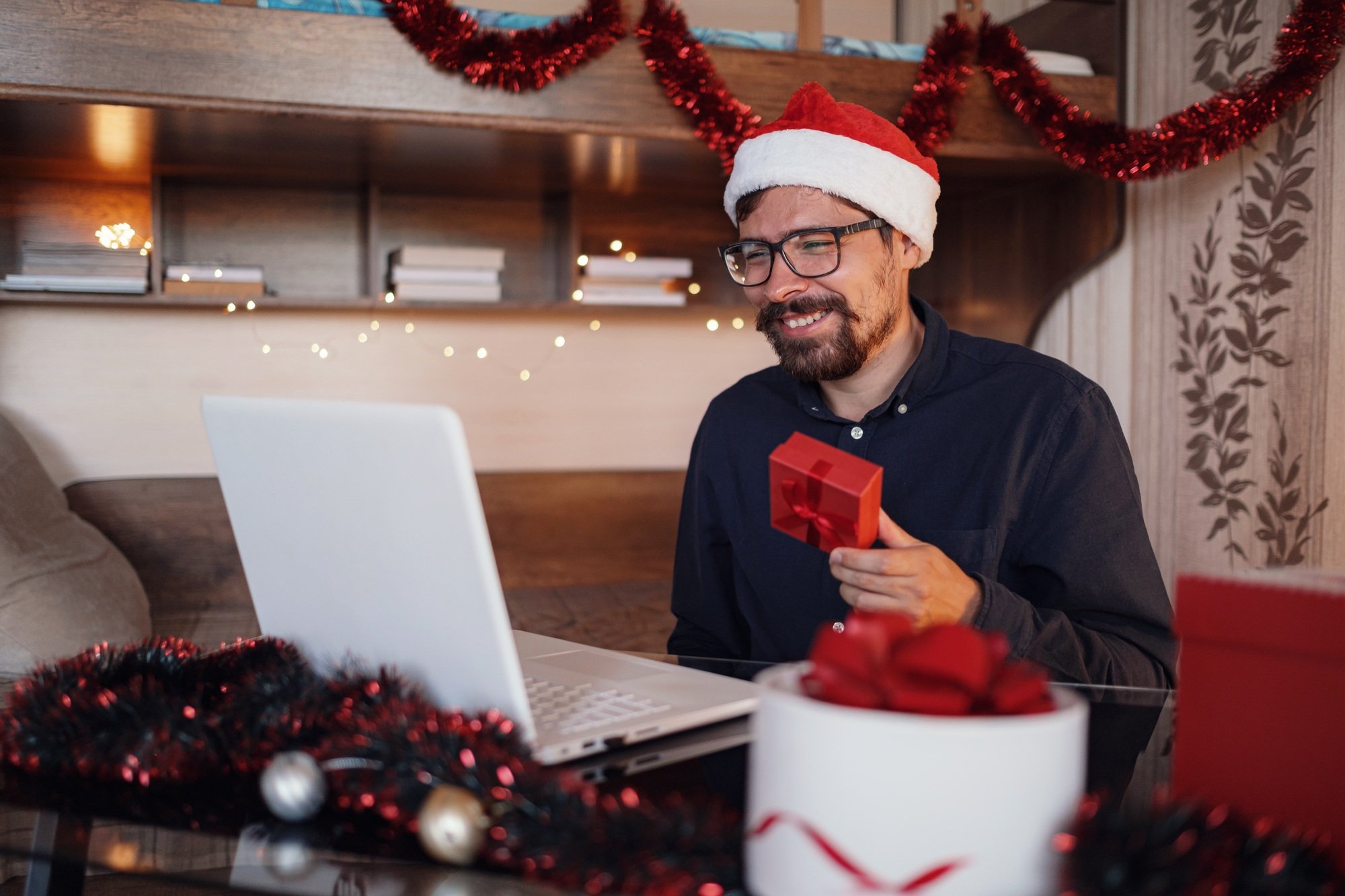 Virtual Christmas day house party. Man smiling wearing Santa hat