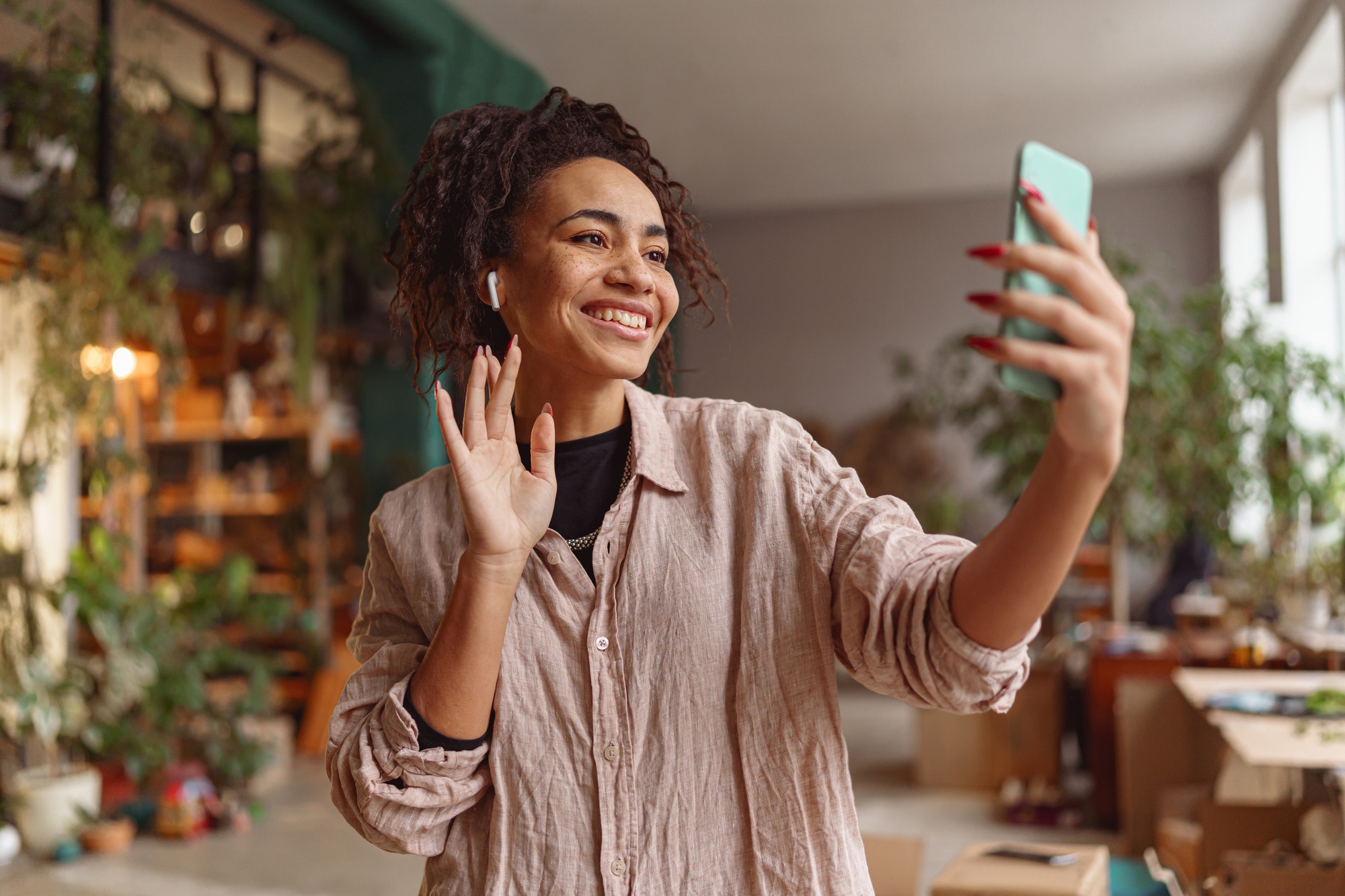 Woman florist making video call to friends during break in floral design studio