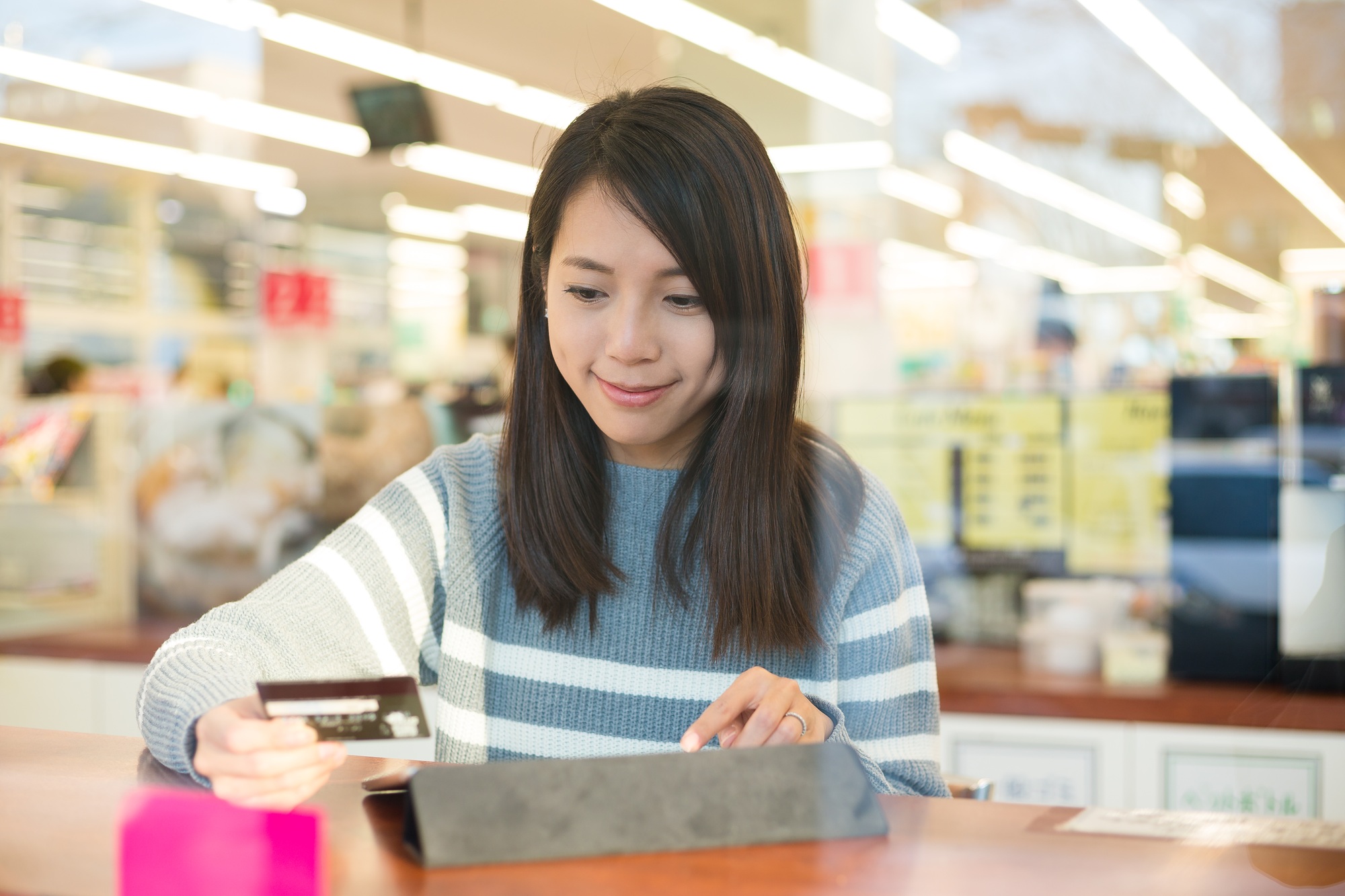 Woman using credit card and touch pad for online booking ticket