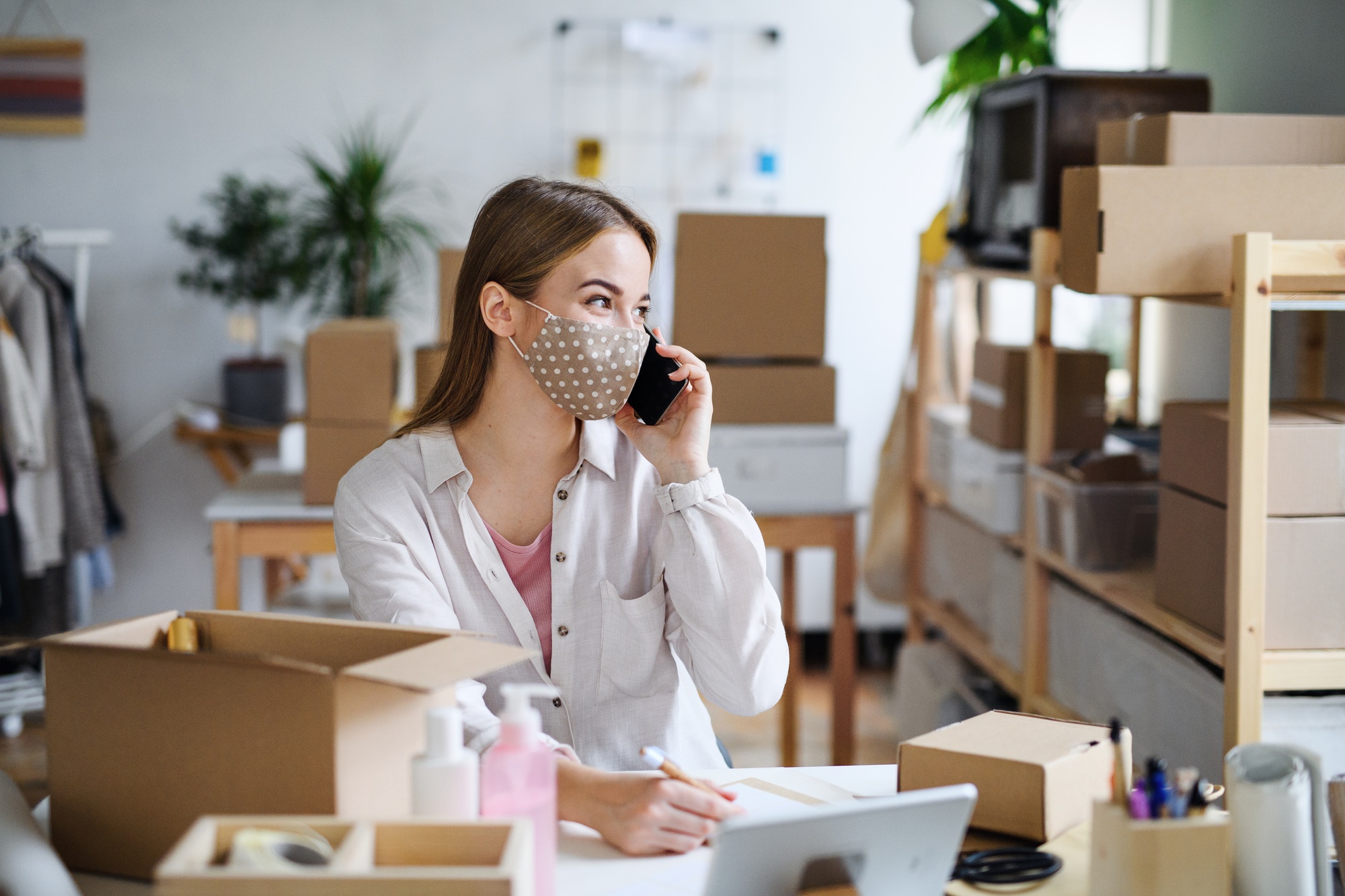 Young woman dropshipper with smartphone working at home, coronavirus concept.