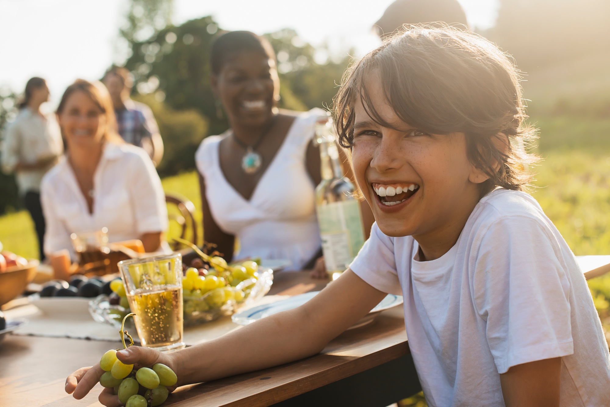 A family and friends having a meal outdoors.  A picnic or buffet in the early evening.