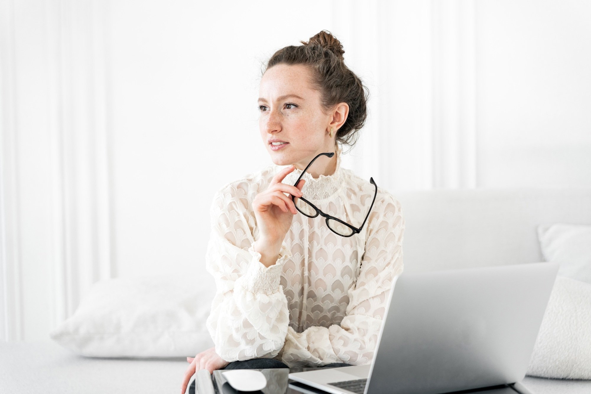 A female seo specialist with glasses uses a laptop. Business office clothes, shirt at the workplace.