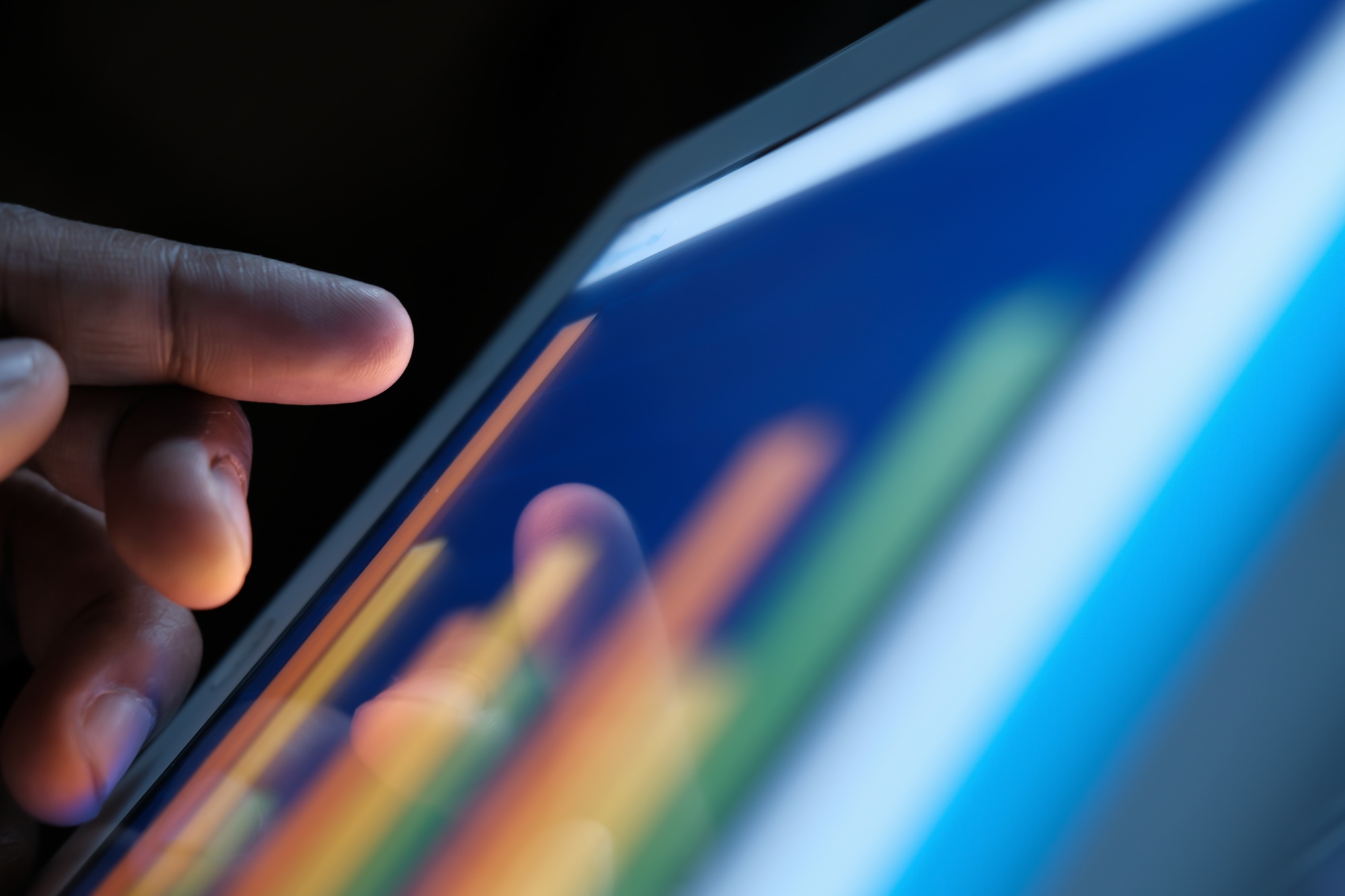 A hand interacting with a data visualization on a tablet screen, highlighting modern technology