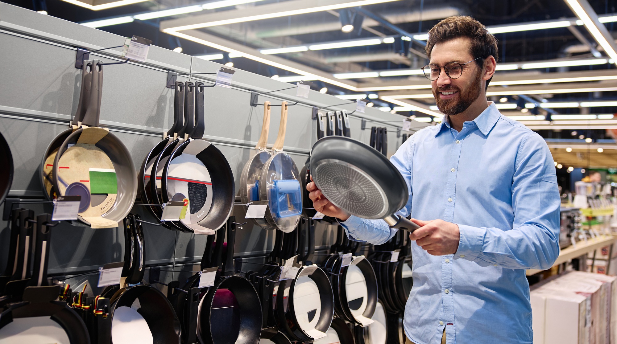 A man is shopping for various cookware items at a Home Goods store for his kitchen needs
