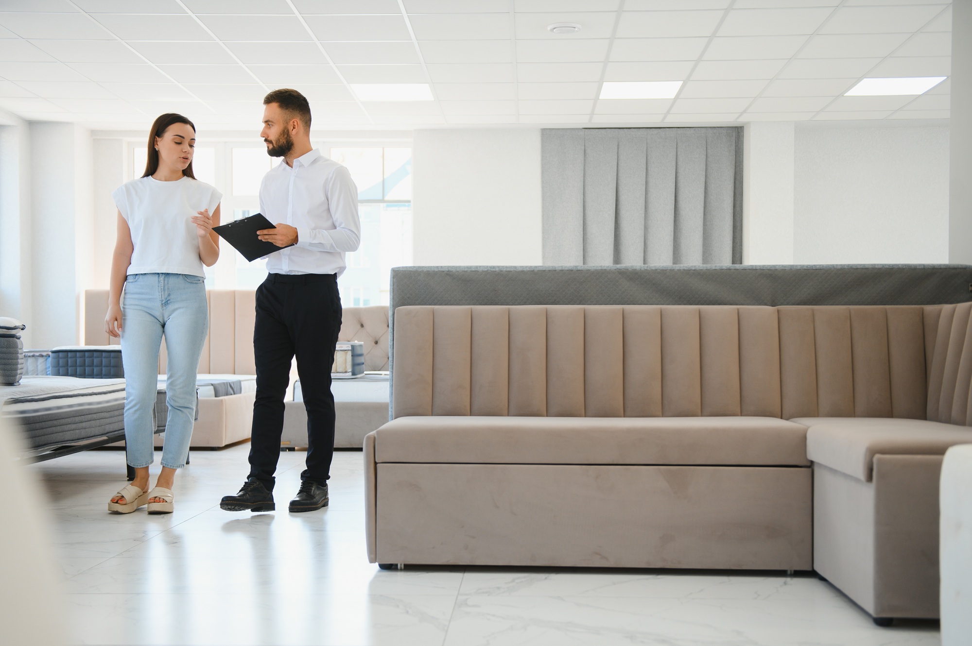 A professional sales consultant advises a client in a furniture store.