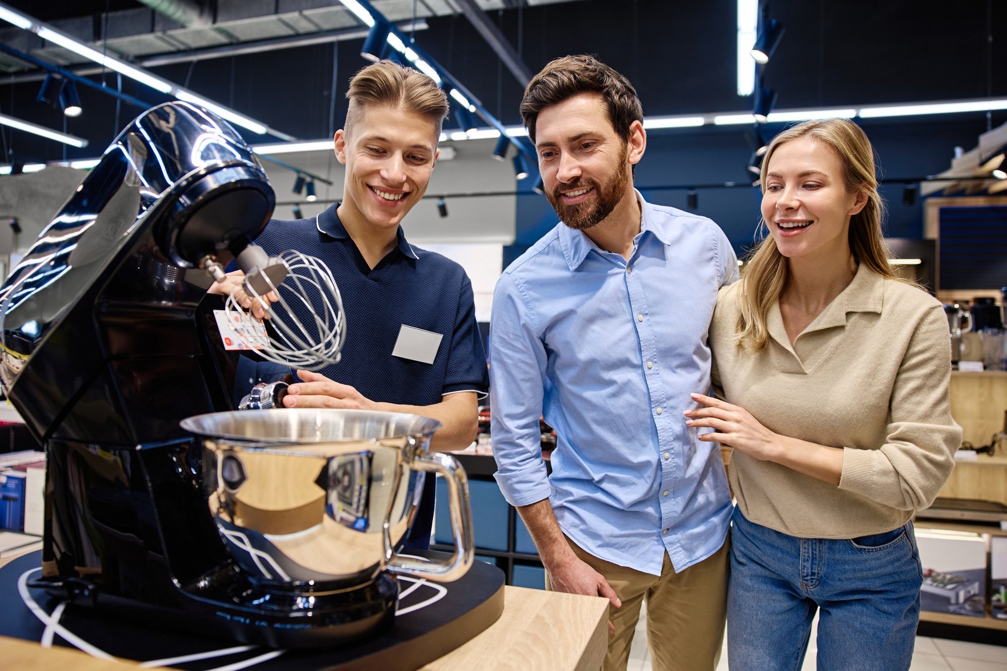 A Sales Associate showcases a kitchen appliance to customers, emphasizing its features