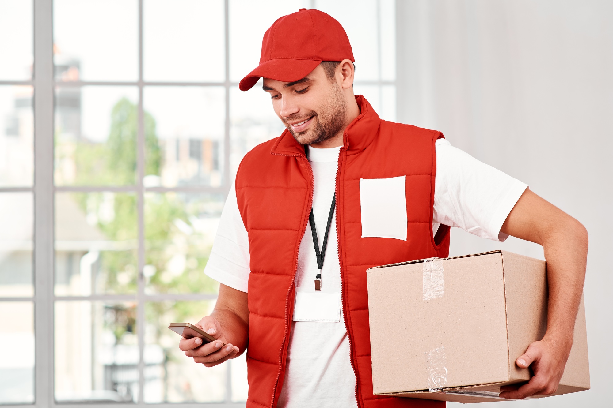 A satisfied customer is the best business strategy. Cheerful postman holding parcels and looking for