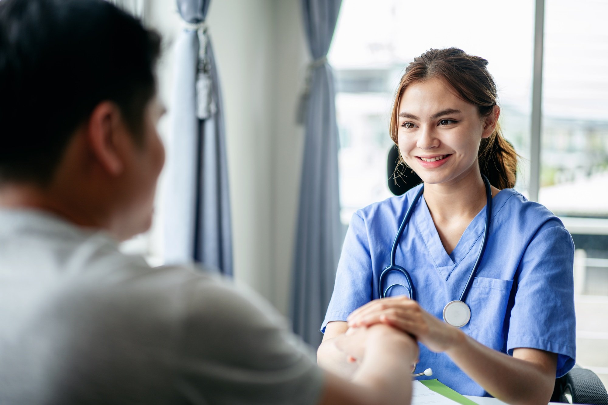 A woman in a blue scrubs is talking to a man