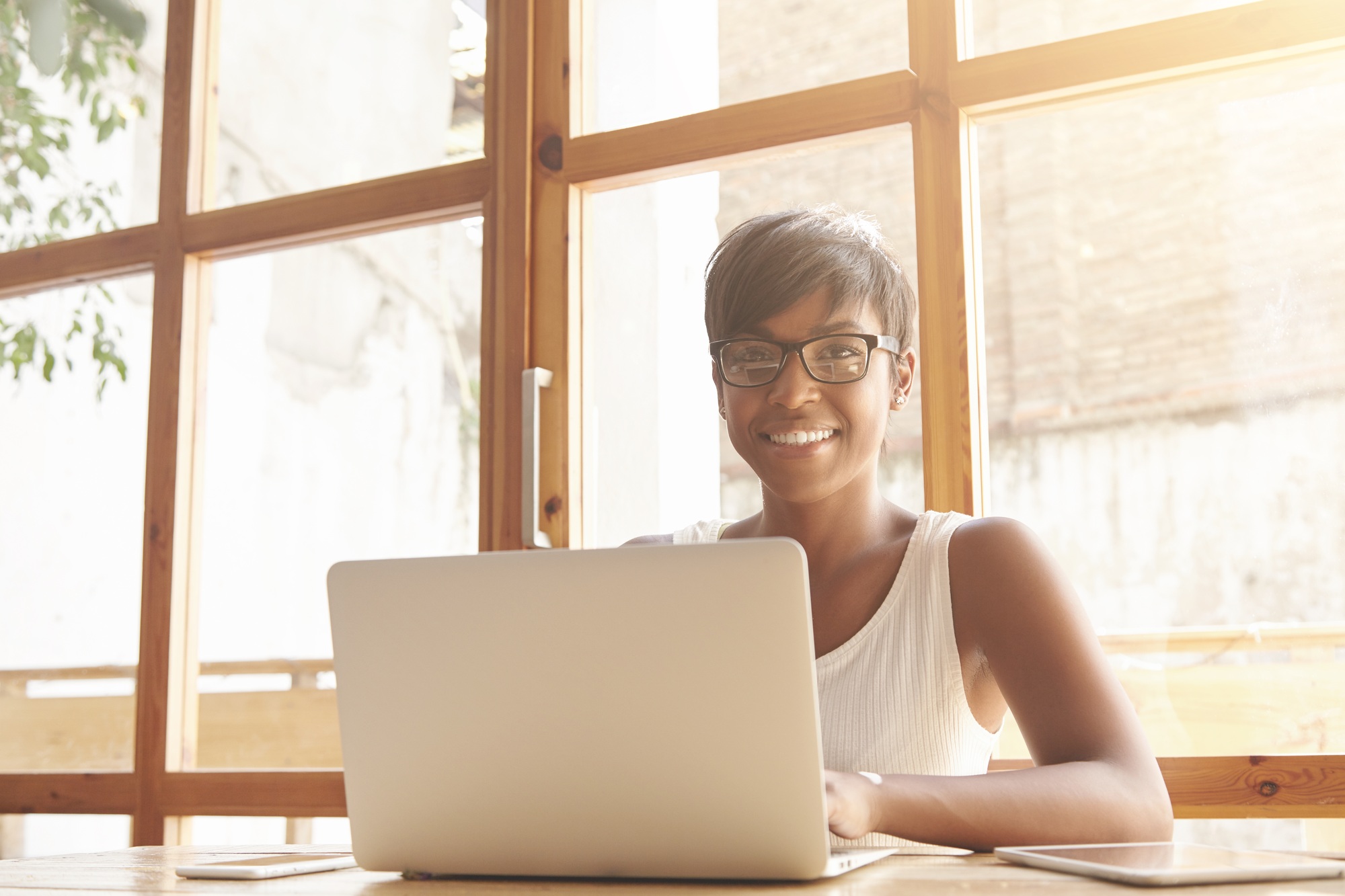 Adult self-confident smiling dark-skinned female web manager dressed casually looking at the camera
