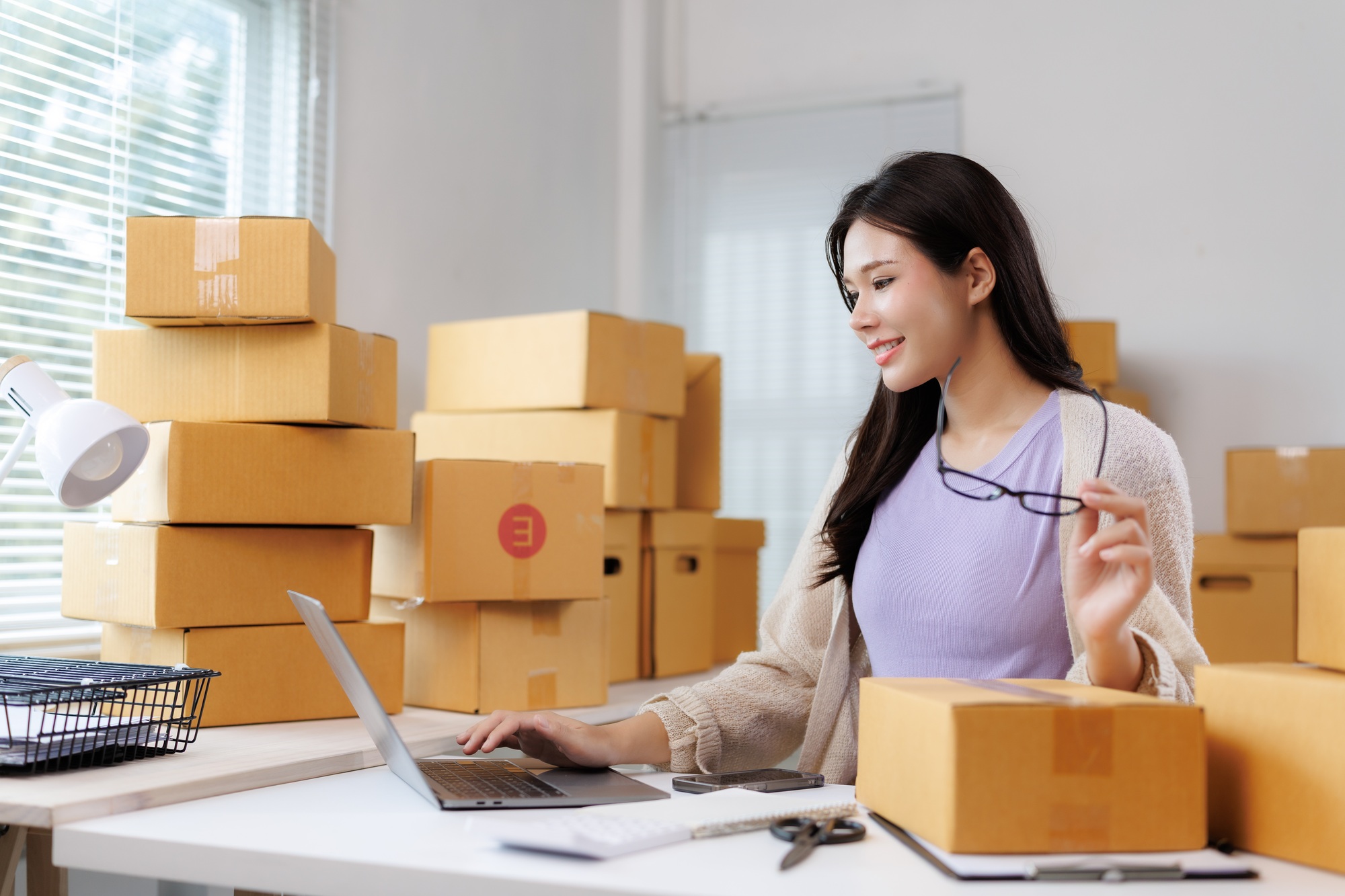 Asian female entrepreneur managing online sales from home office