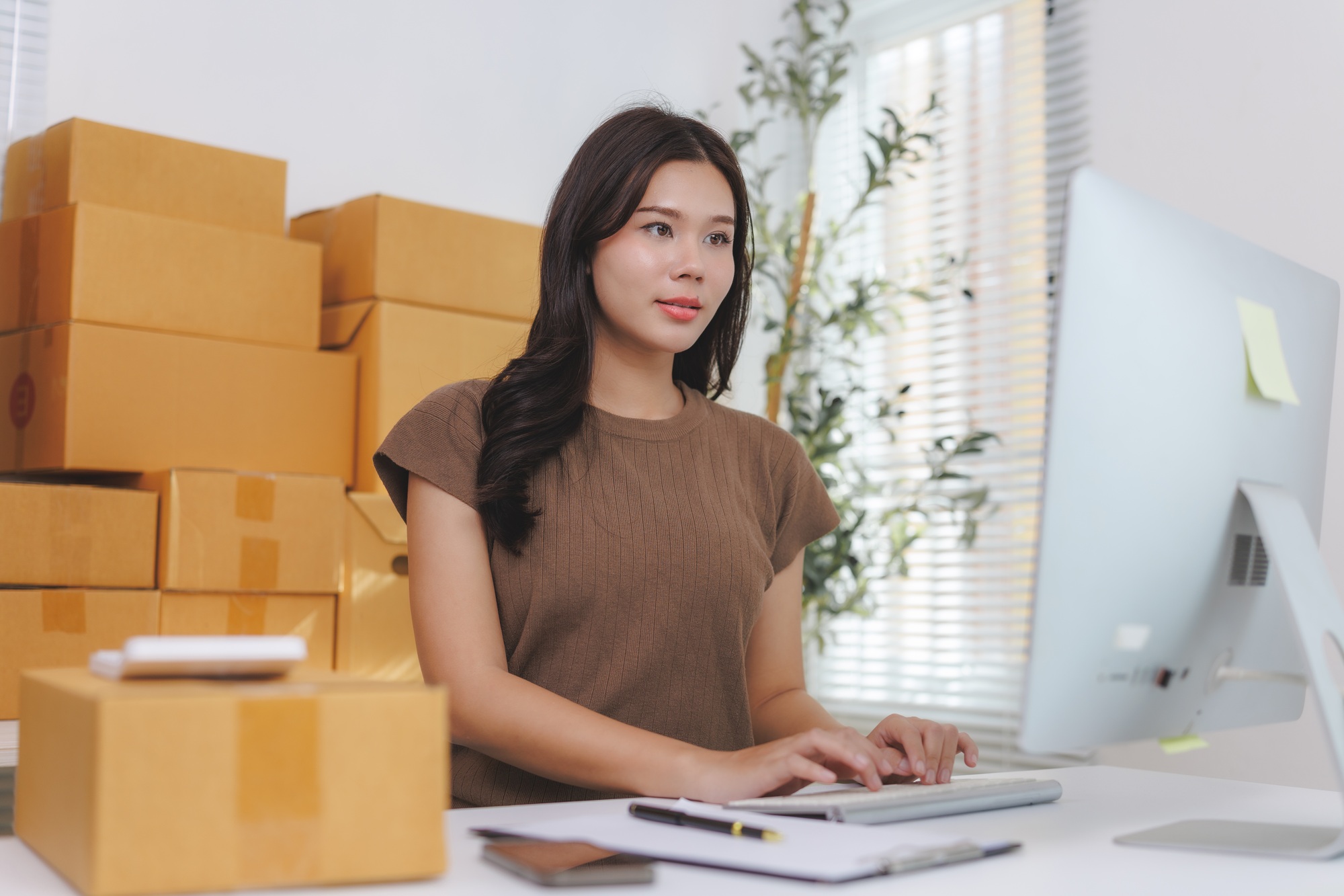 Asian woman entrepreneur typing on keyboard and managing online sales