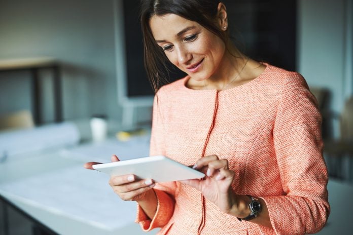 Attractive elegant successful female branding consultant looking to the screen of her tablet in the
