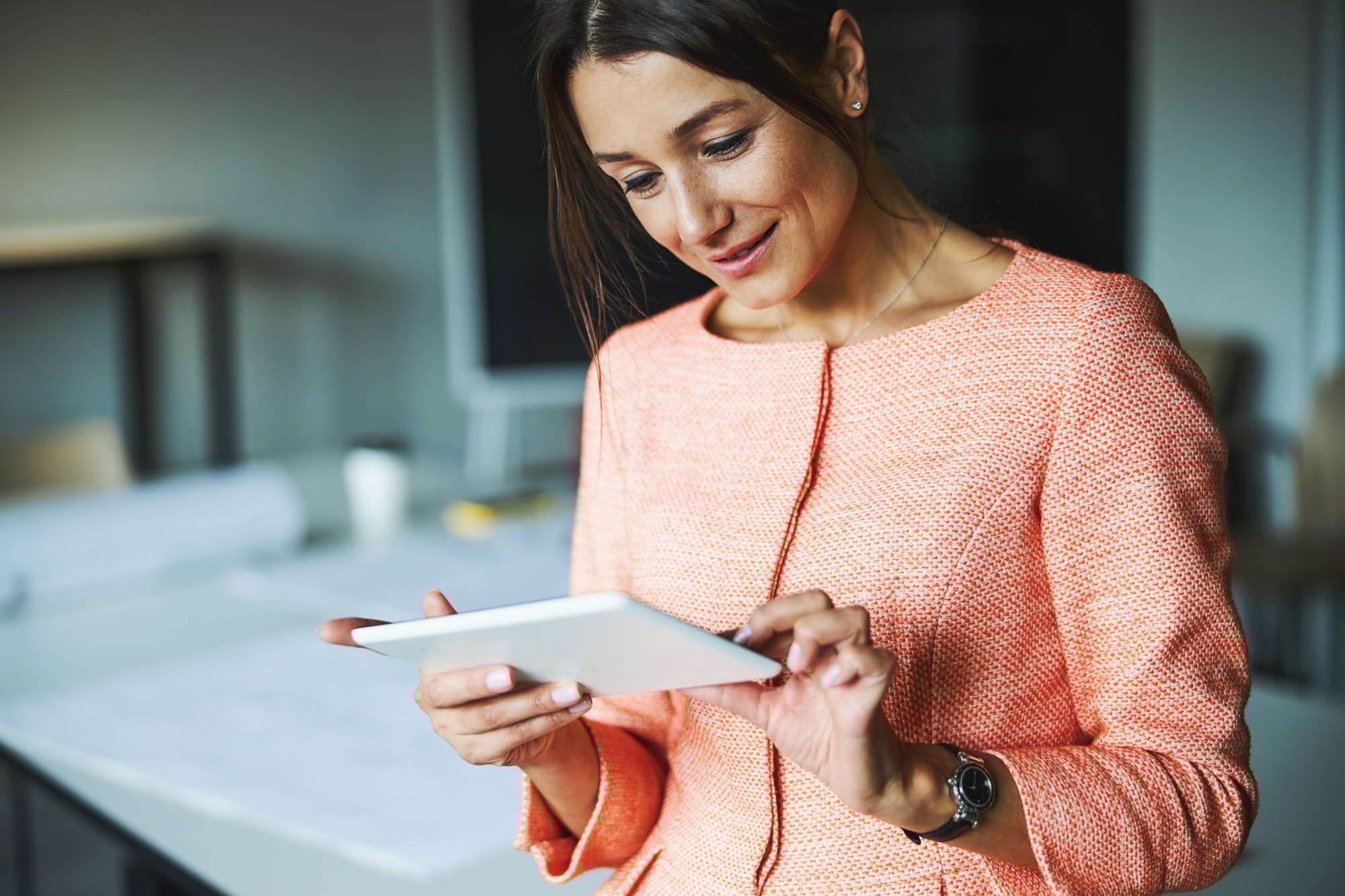 Attractive elegant successful female branding consultant looking to the screen of her tablet in the